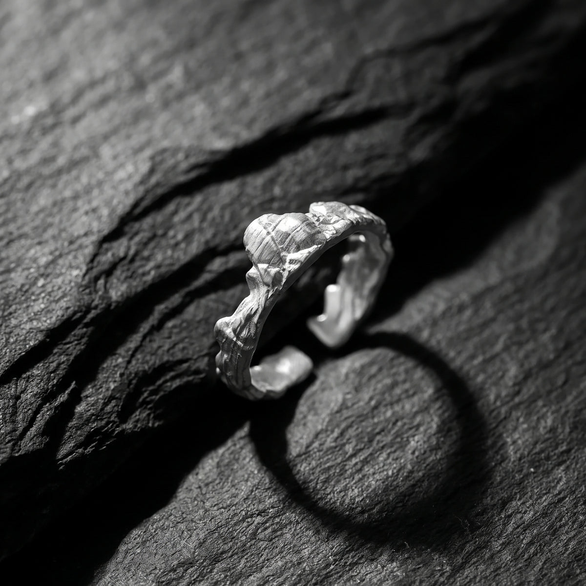 Angled close-up of the silver mountain ridge ring on dark stone, showcasing its open-band design.