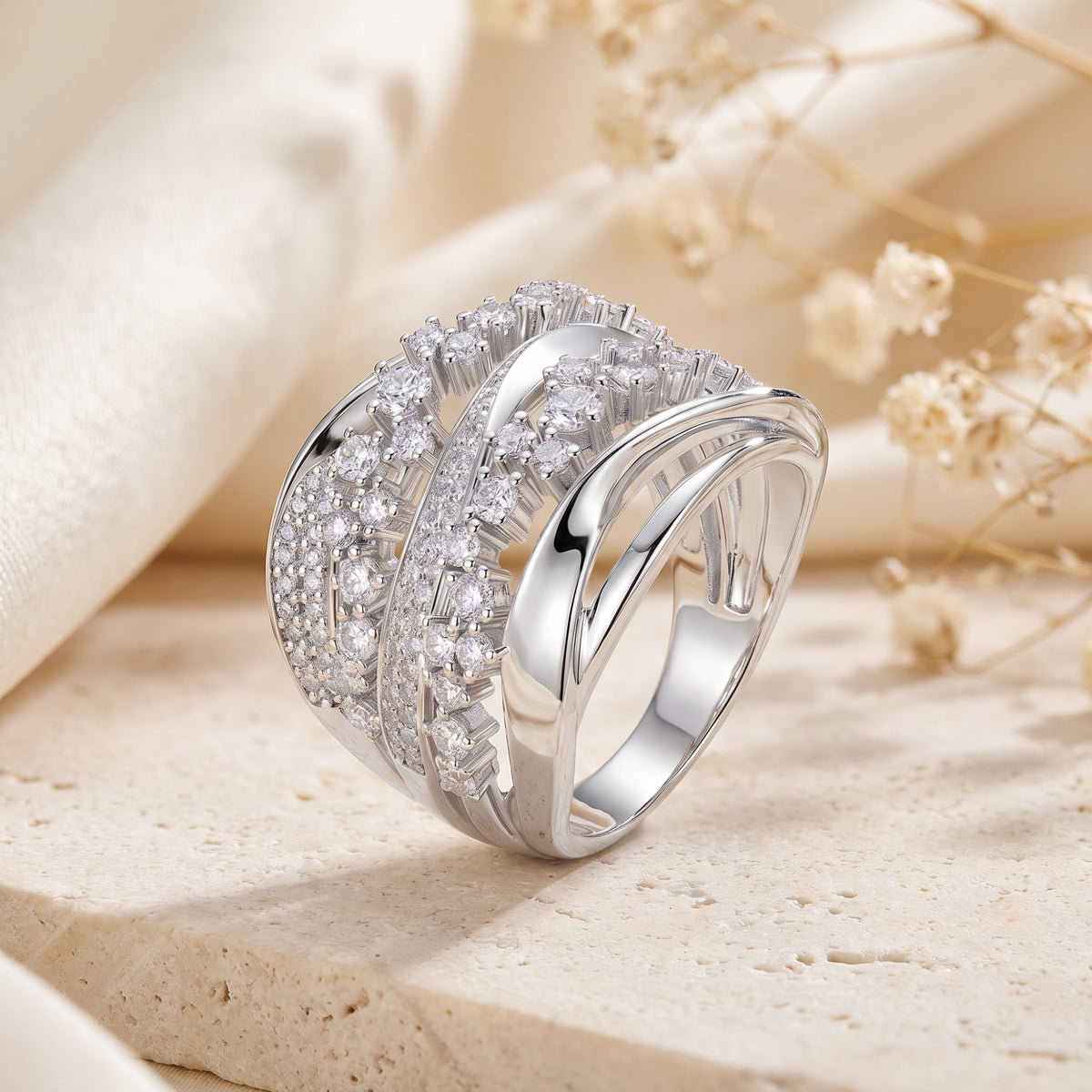 Three-quarter view of the silver crossover ring showing its polished inner shank and multiple rows of clear stones.