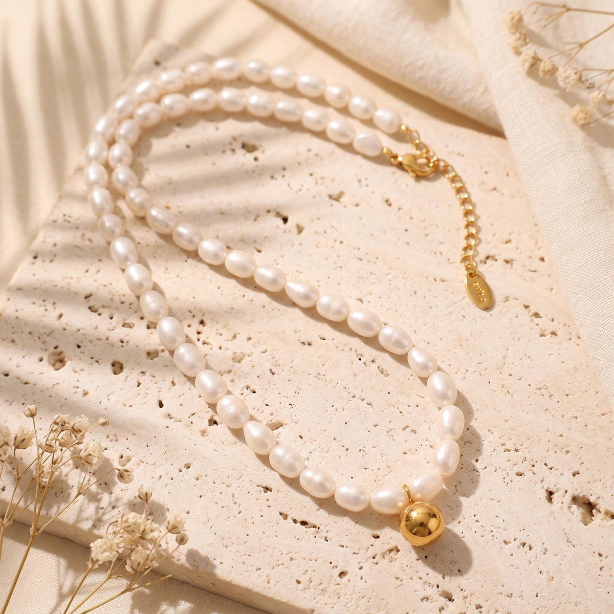 Full necklace laid flat, showing the gold-tone sphere pendant, lobster clasp, and extender chain.