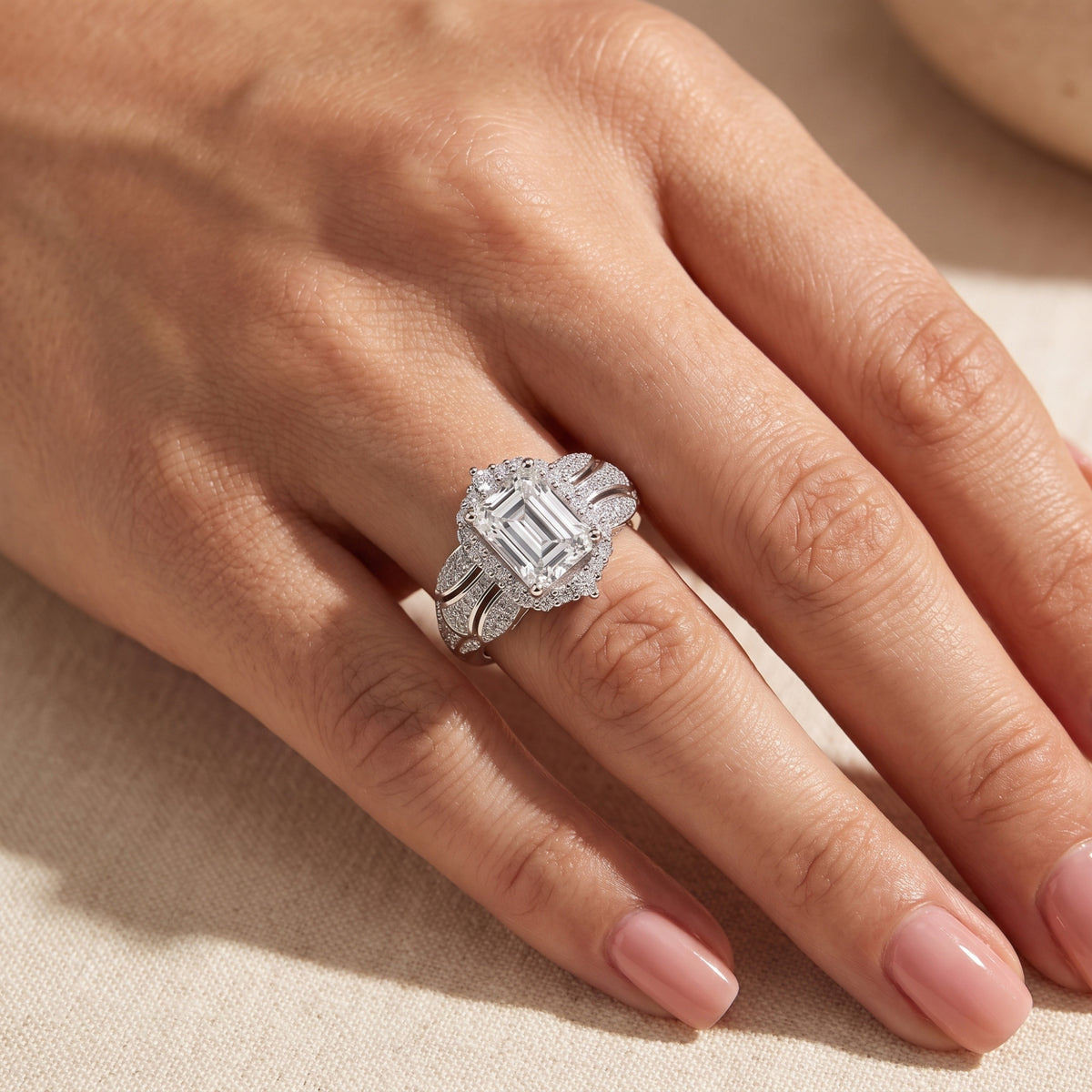 Overhead view of the emerald-cut halo ring worn on a hand, highlighting the center stone and halo details.
