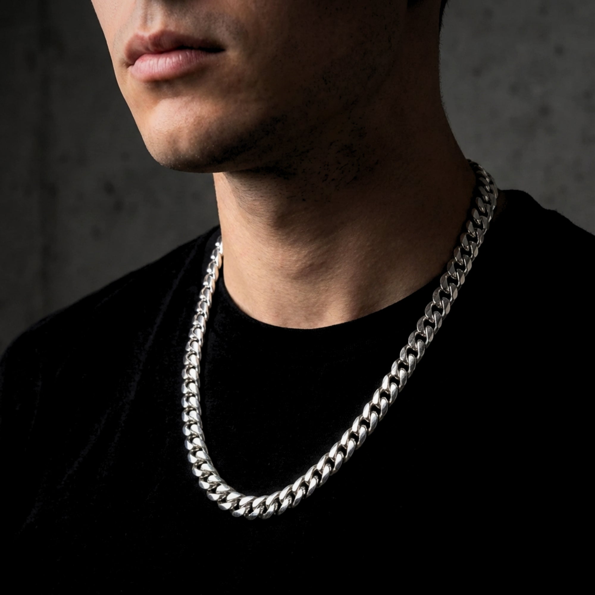 10mm silver stainless steel Cuban link chain worn by a model against a dark background.
