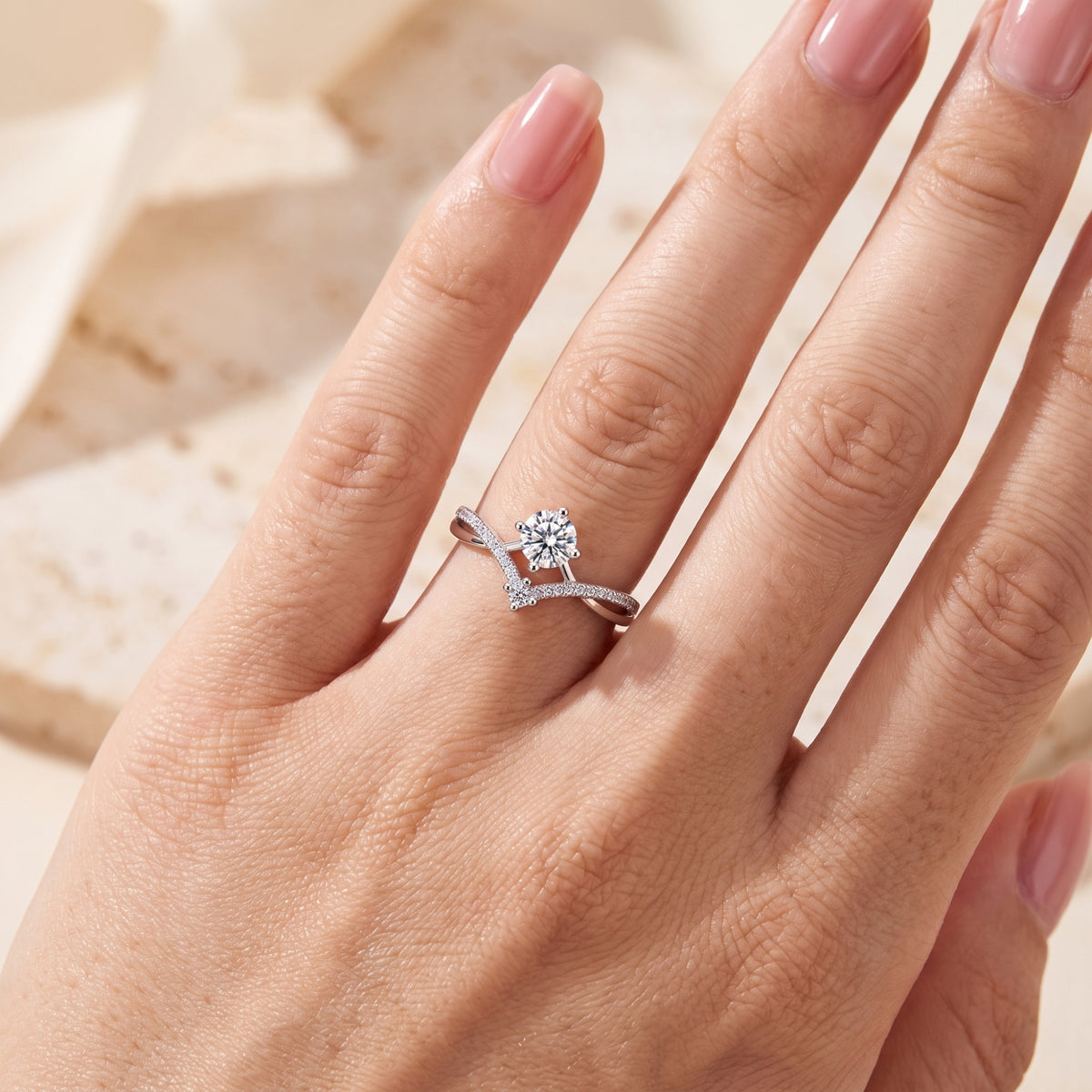 Close-up of a hand wearing the silver chevron ring, showing its nested pavé wishbone shank and clear round stone.