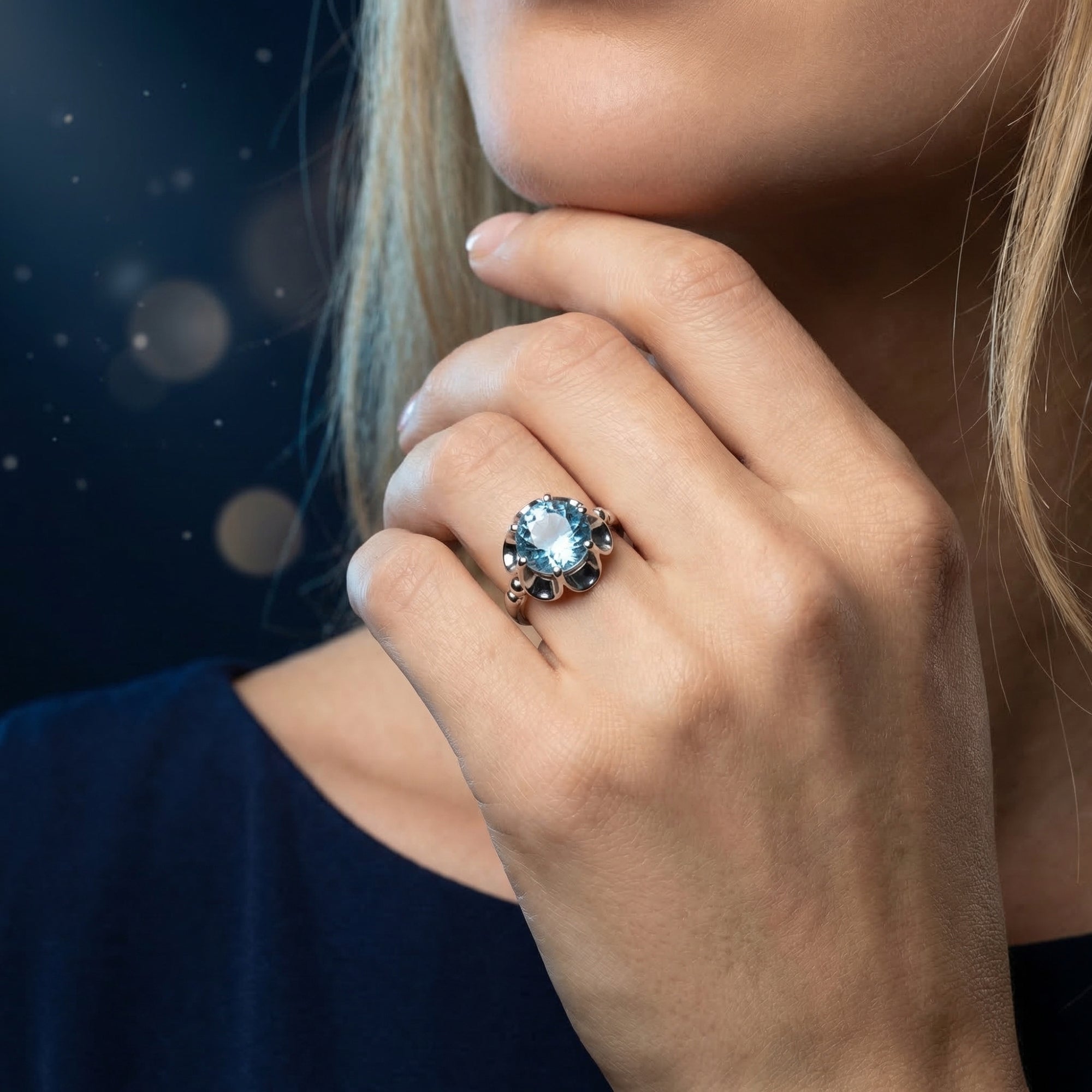 Aethra natural blue topaz ring in sterling silver worn by a model in a dark blue dress.