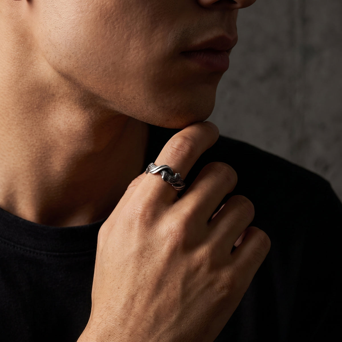 Model touching his chin while wearing the textured silver twist open band ring on his index finger.