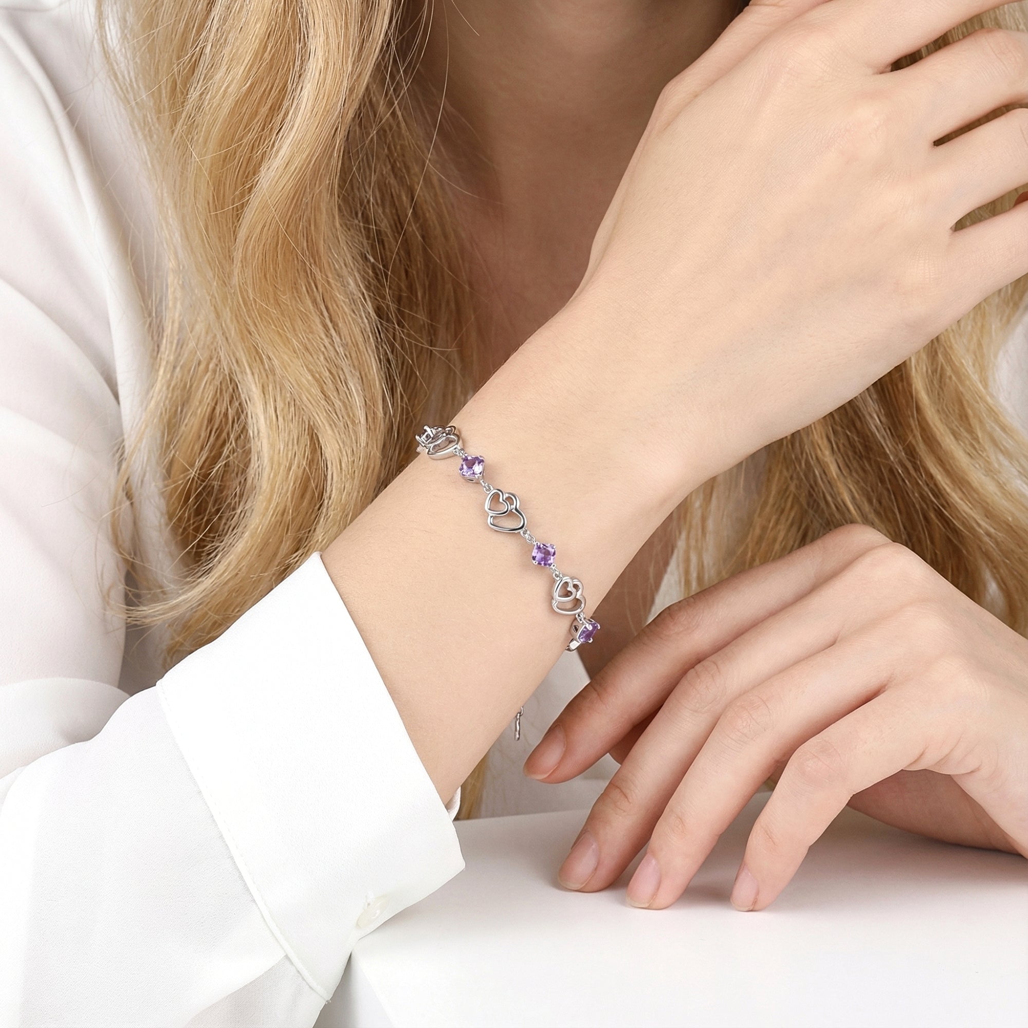 Side view of the sterling silver heart link bracelet with purple amethyst stones on a woman's wrist.