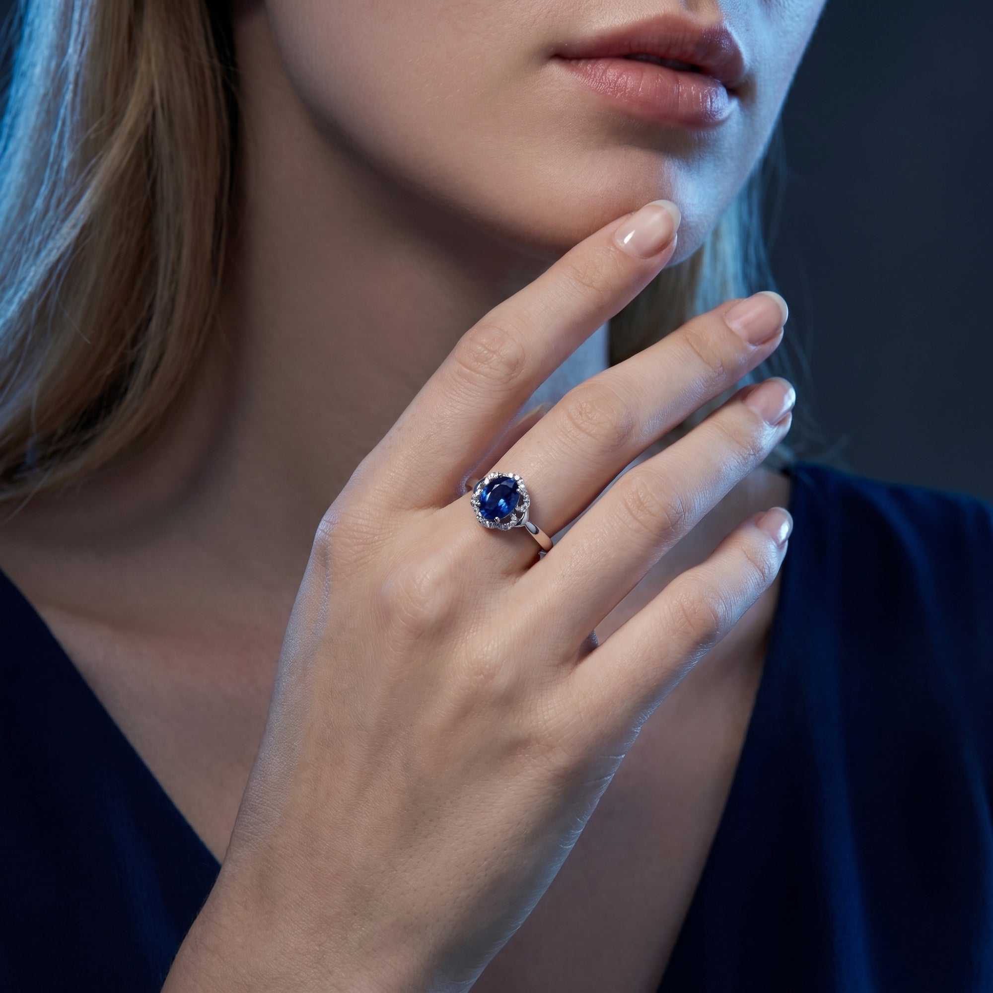 Model wearing the Vesperina 18K white gold oval tanzanite halo ring, paired with a dark blue dress.