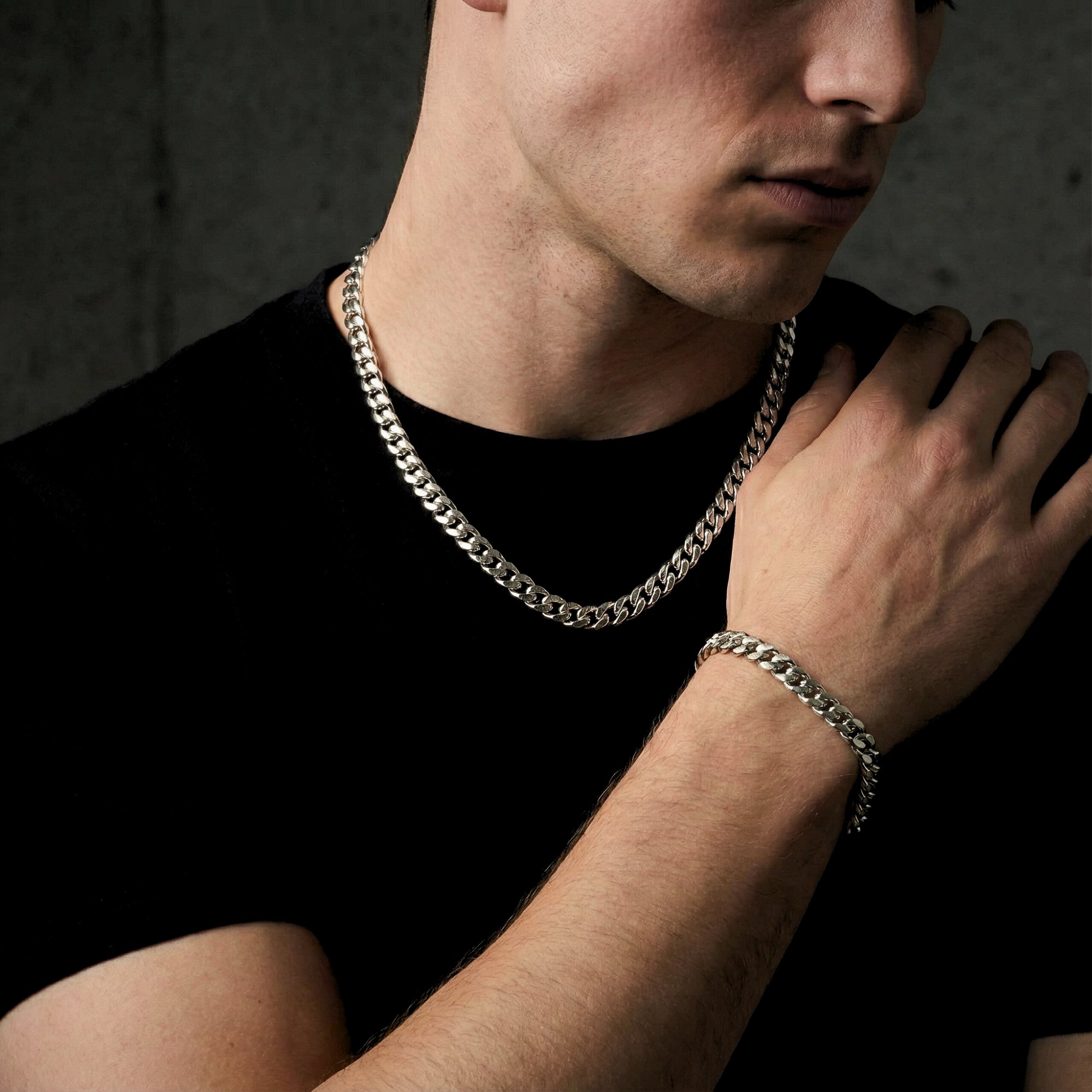 Side view of a model wearing the silver stainless steel Cuban link chain and bracelet set.