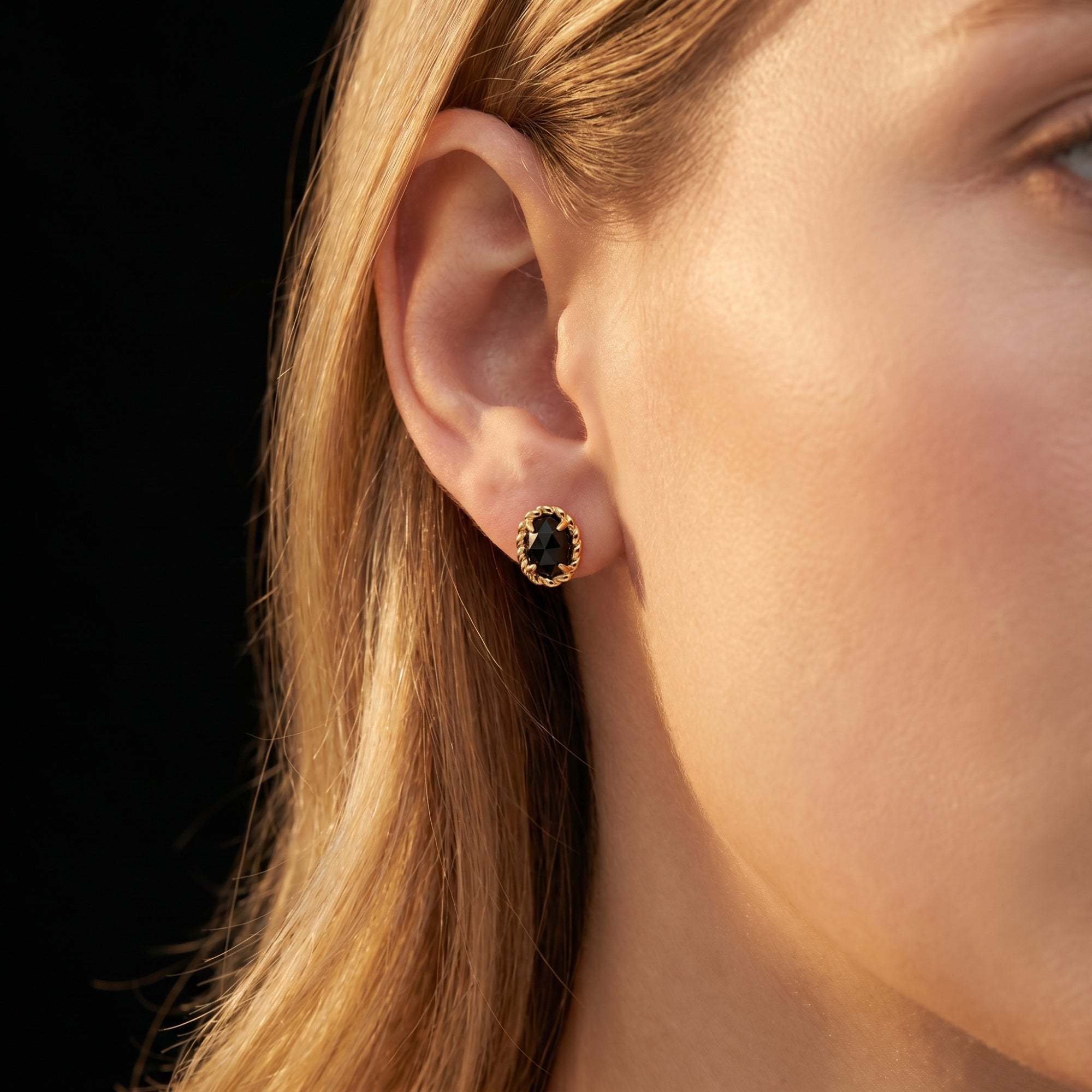 Side view of a model wearing the Avelina twist onyx stud earrings to show scale and fit.