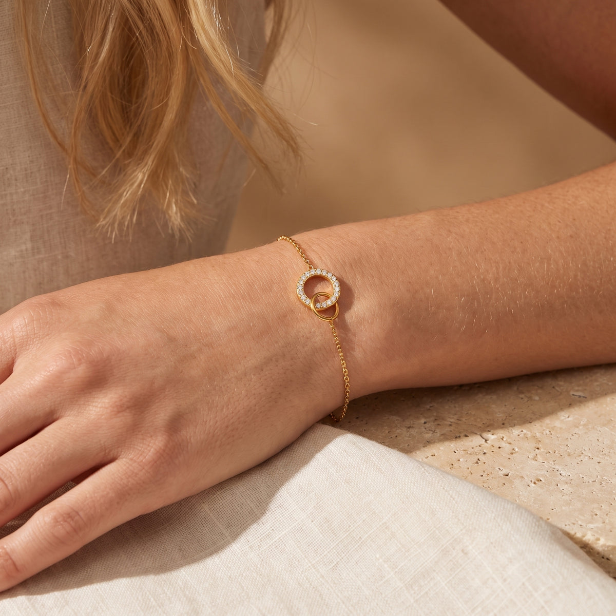 Gold-tone interlocking circle bracelet worn on a hand and wrist, shown from above with the circular centerpiece visible.