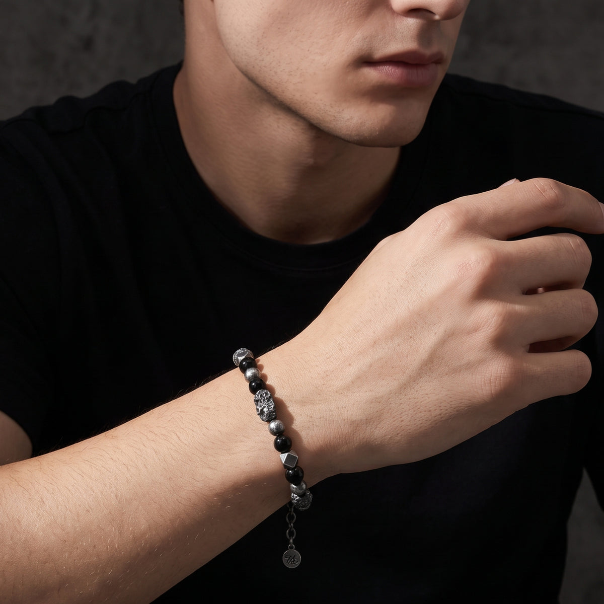 Model wearing the beaded bracelet on his wrist, showing the full design and dangling extension tag.