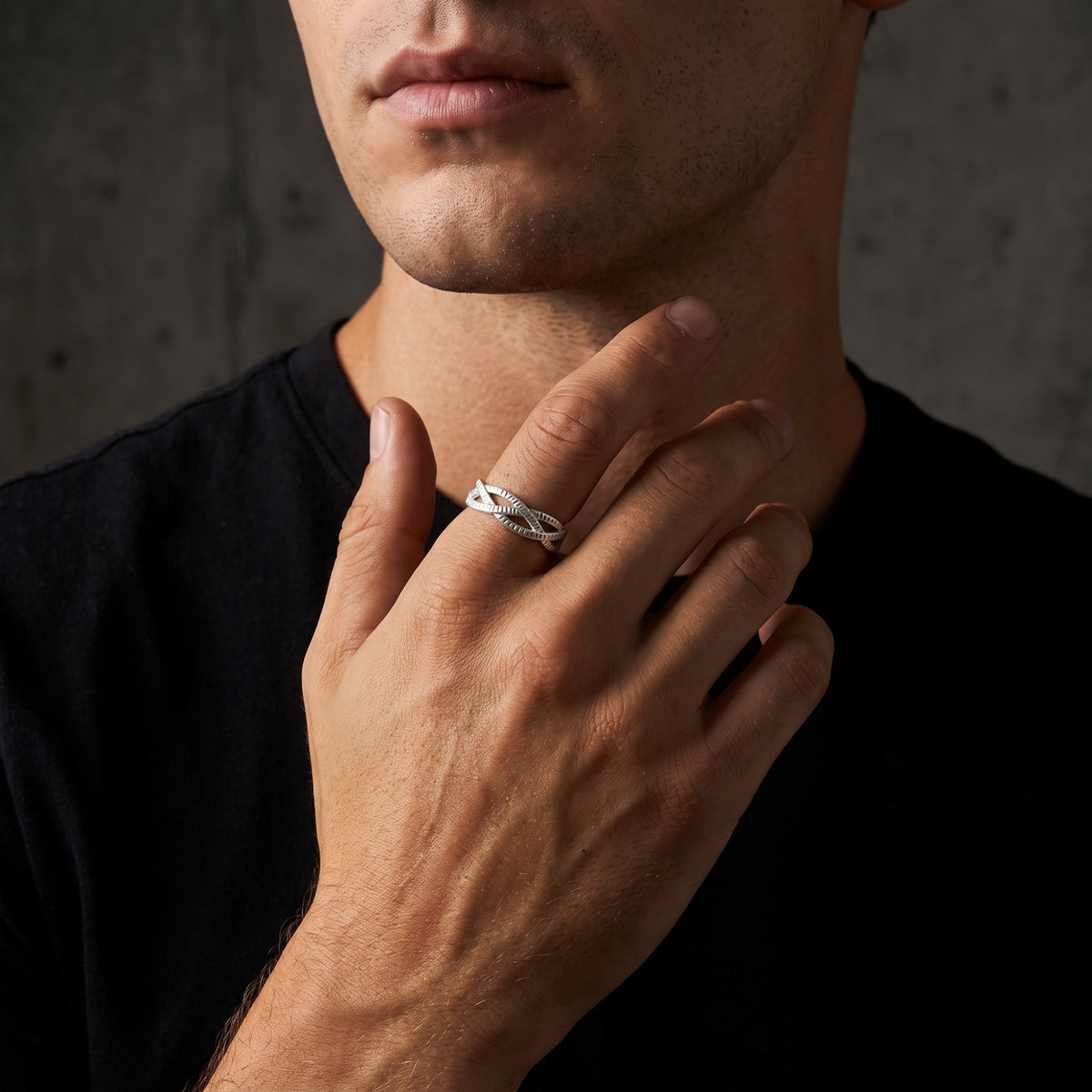 Model wearing the textured silver open ring on the index finger with a hand resting across the neck.