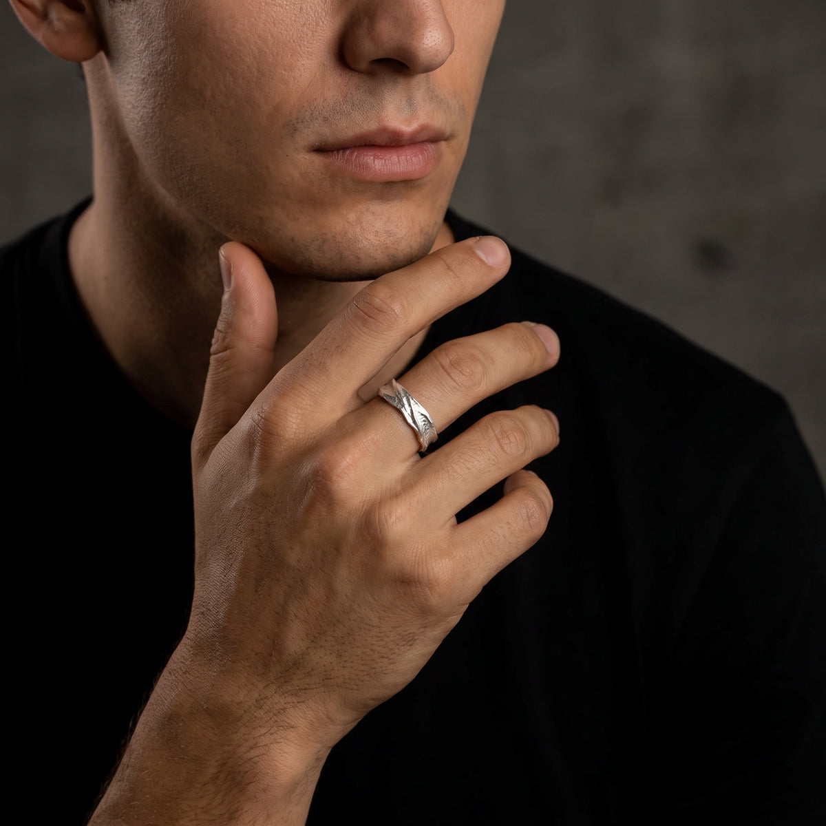 Close portrait of a man wearing the textured fine silver open band ring with his hand raised near his chin.