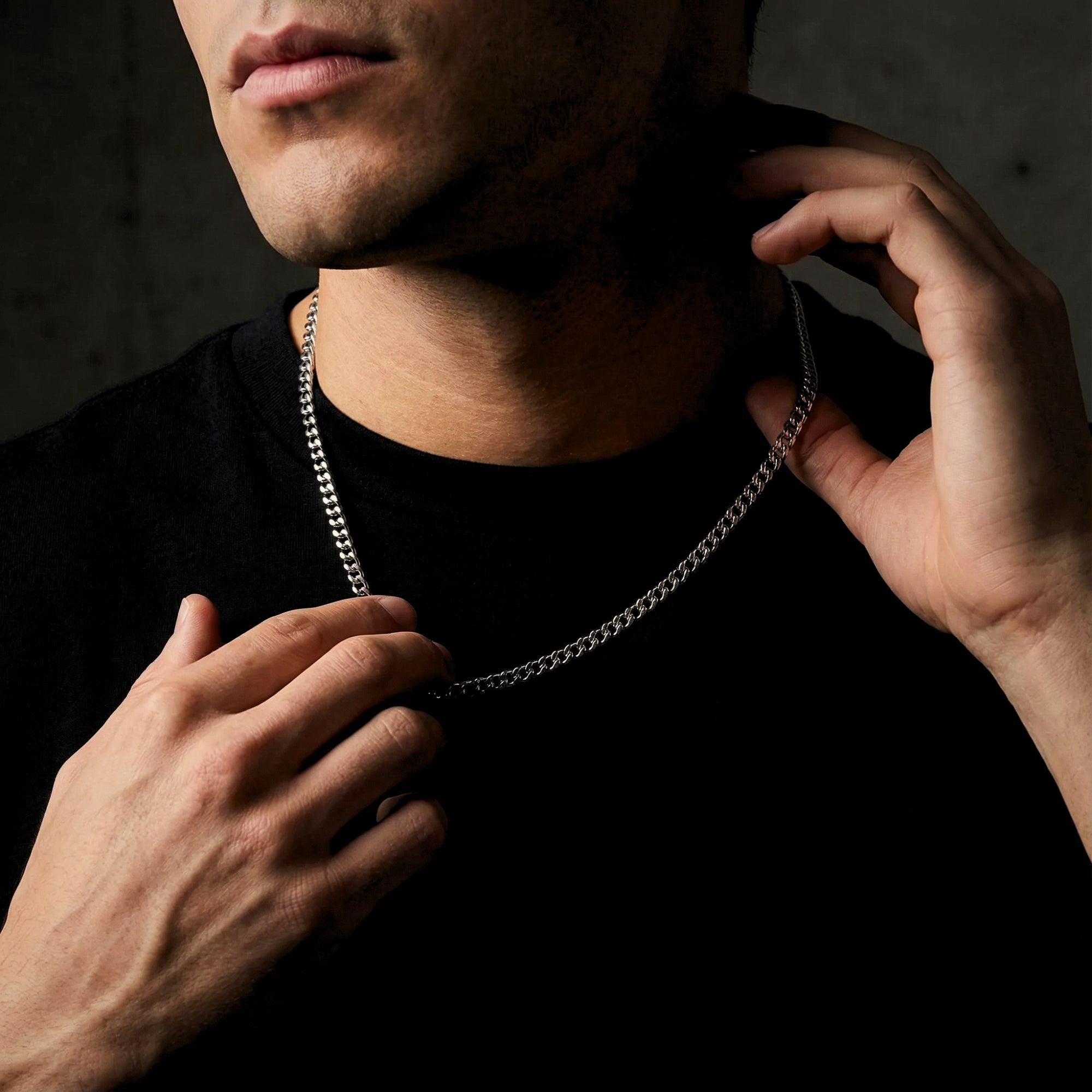 Man adjusting a silver 4mm stainless steel Cuban link chain around his neck.