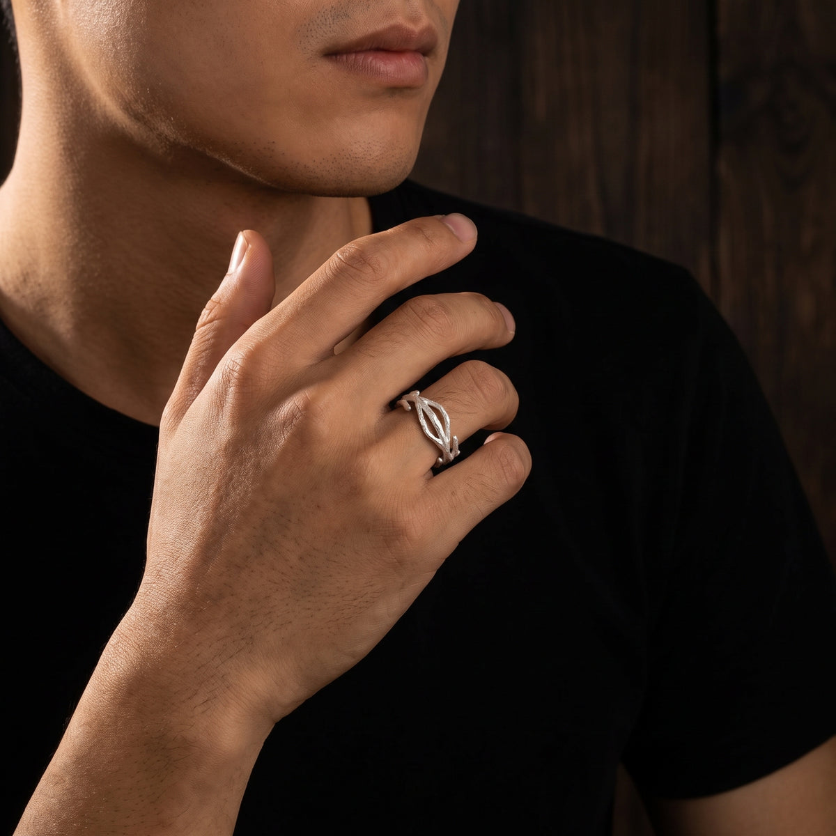 Model wearing the silver open branch ring on a bent finger, with his hand raised near his chin.