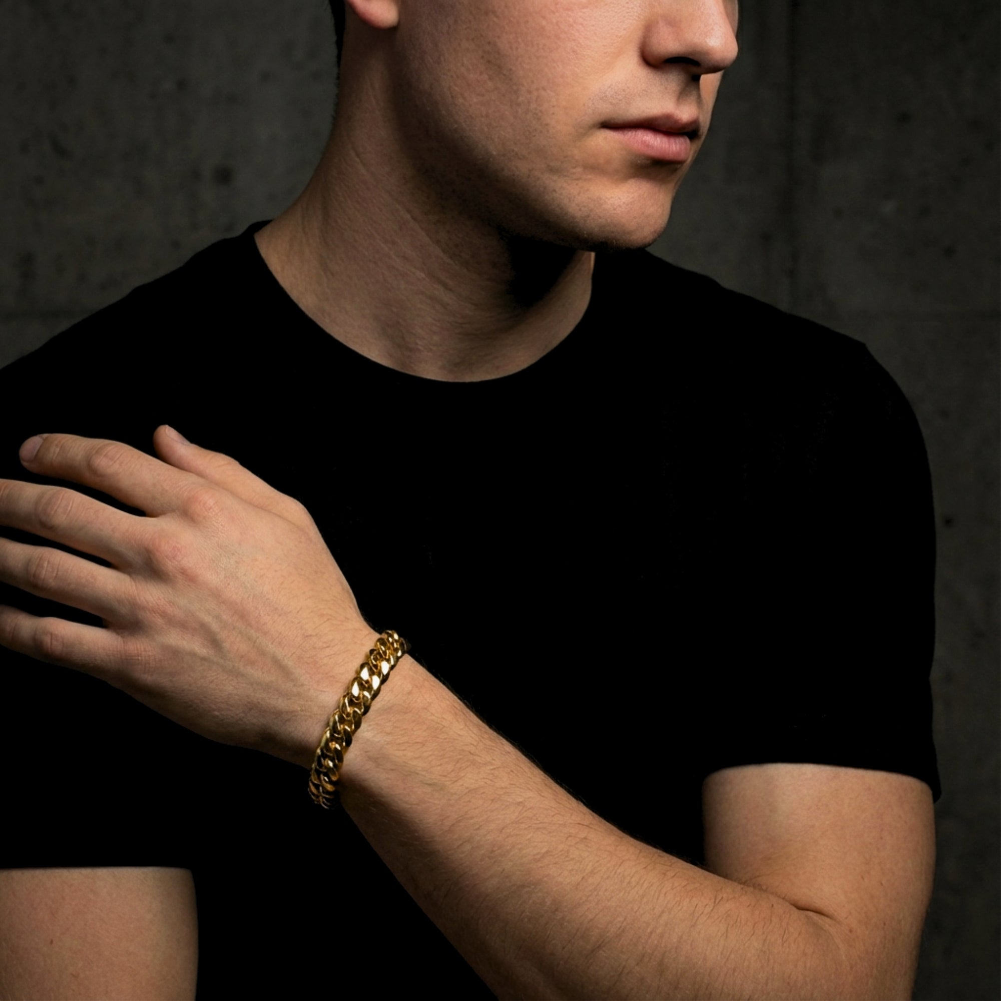 Man wearing a gold Cuban link stainless steel bracelet, styled with a black t-shirt.