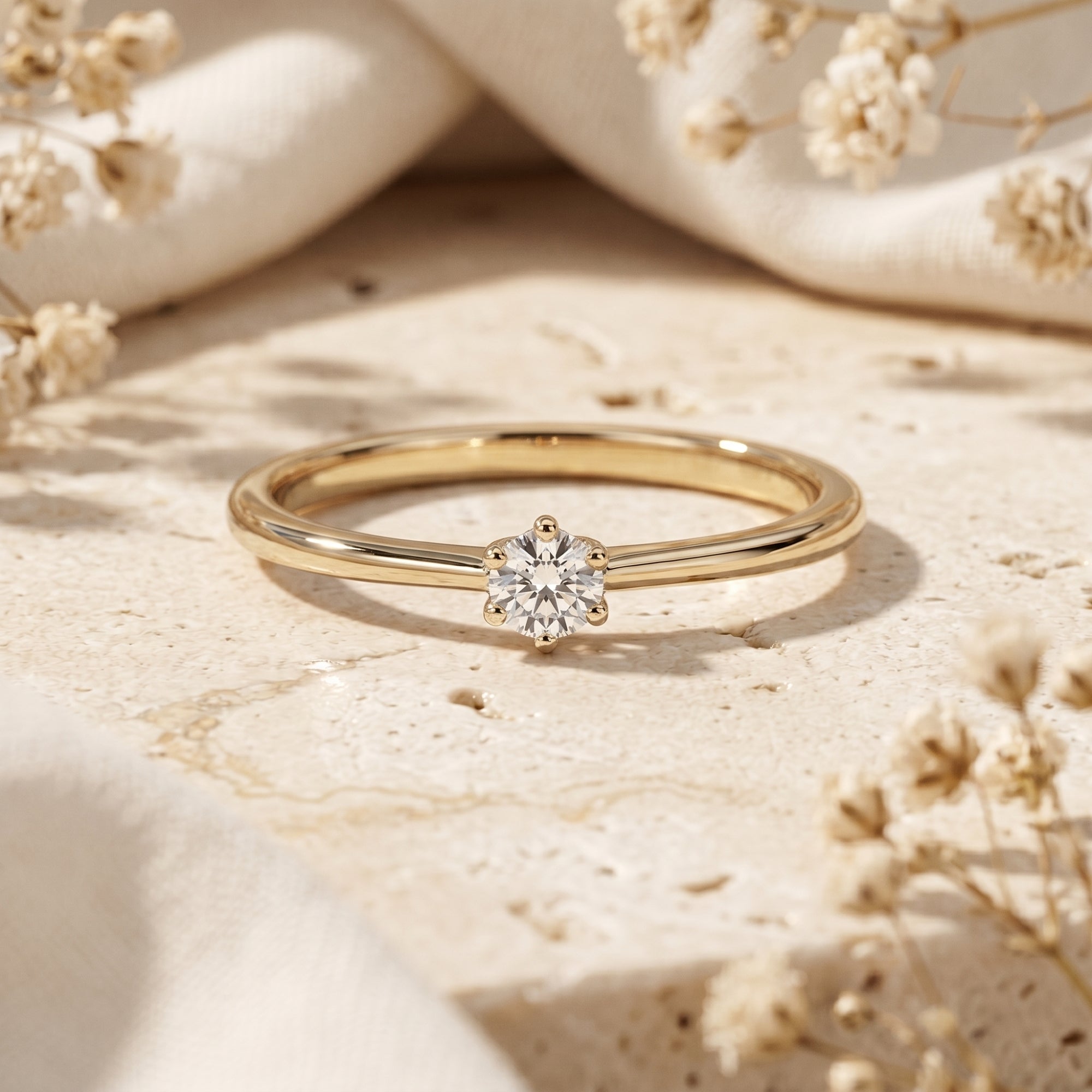 Gold round cut moissanite solitaire ring on a stone surface.