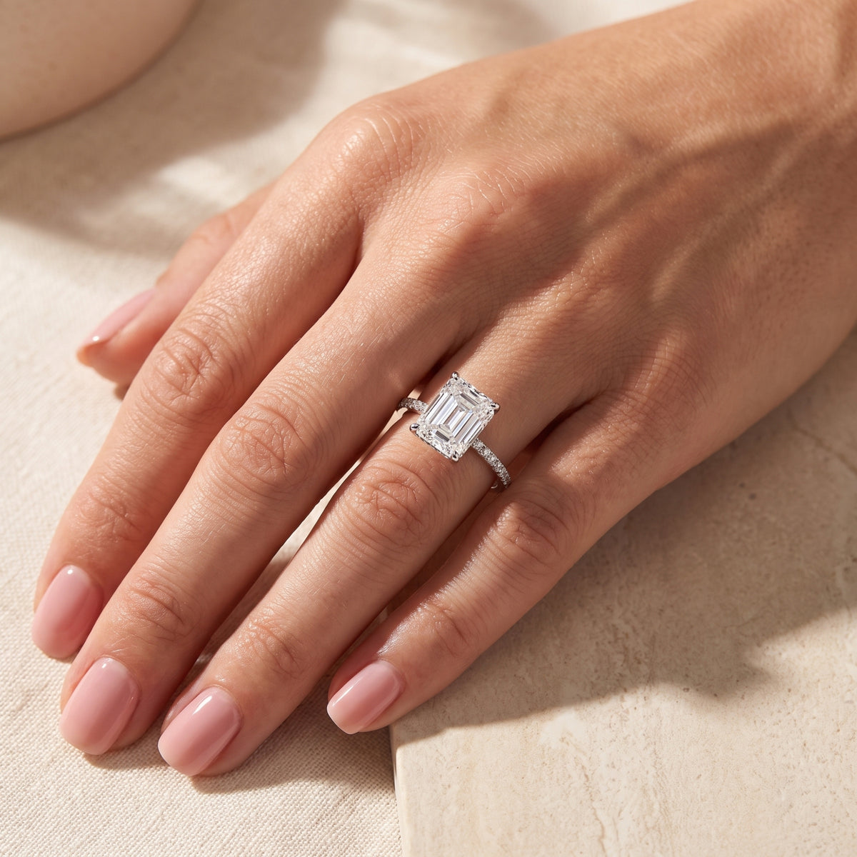 Full hand view wearing the silver emerald-cut clear stone ring with a pavé band.