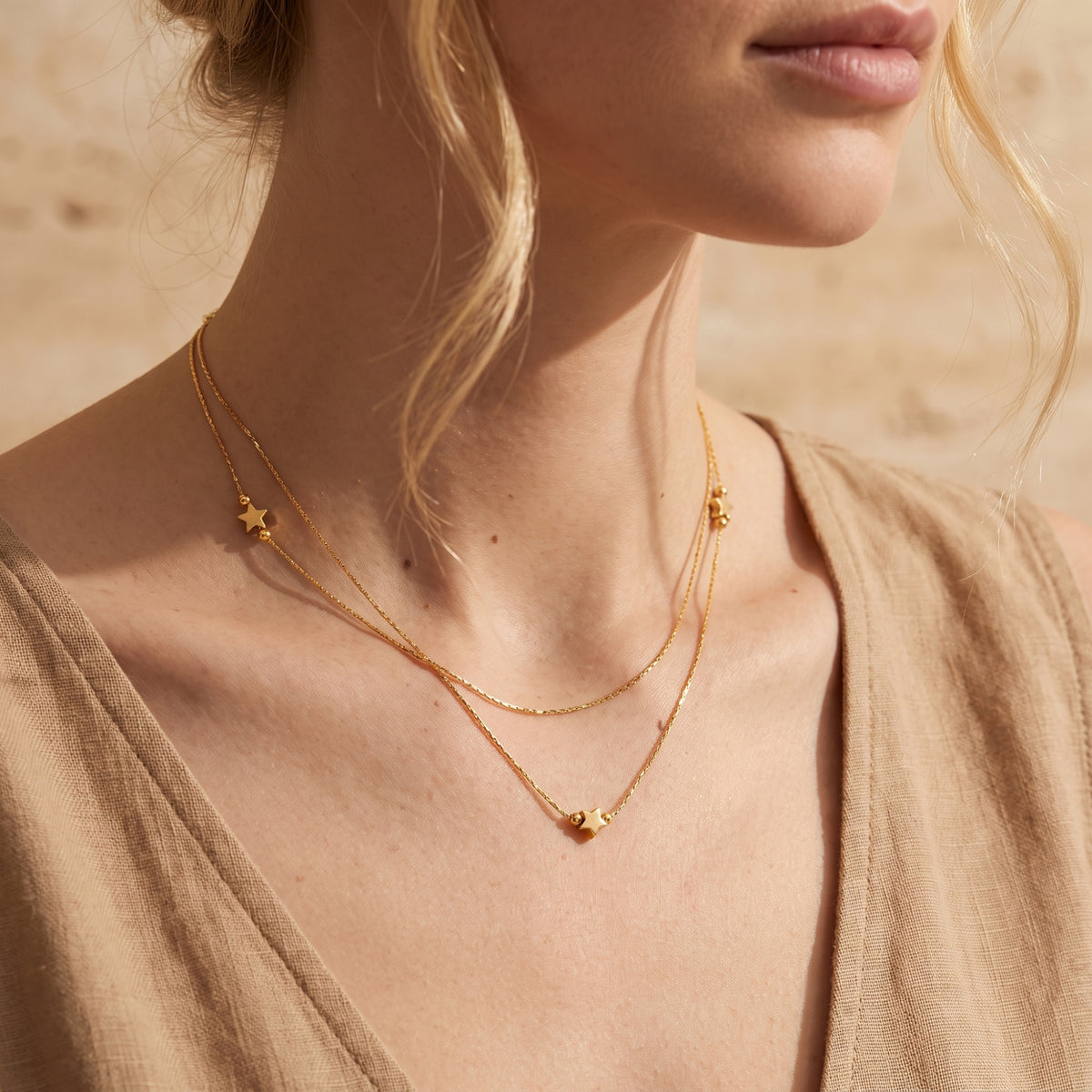 Close-up of a model wearing the gold-tone layered star necklace with a beige outfit.