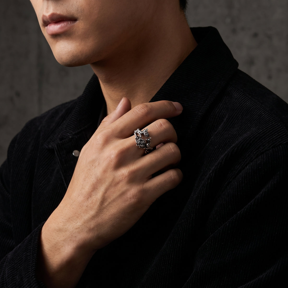 Man wearing the silver rose vine open ring on his middle finger with a black corduroy jacket.
