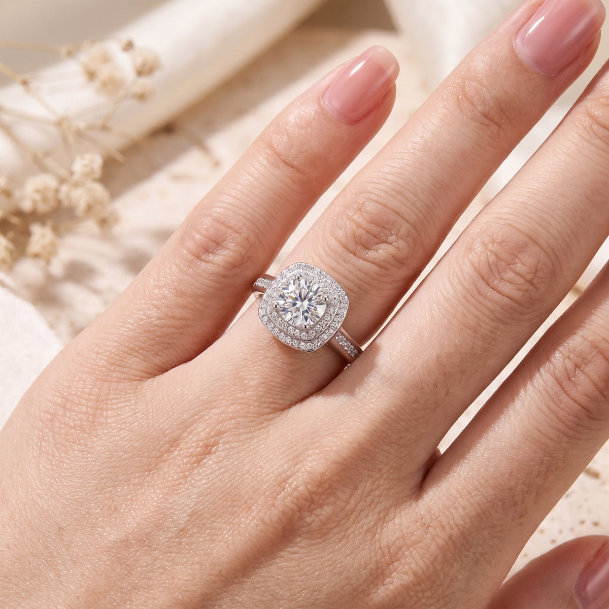 Close-up of the silver double halo ring worn on a hand with pale pink manicured nails.