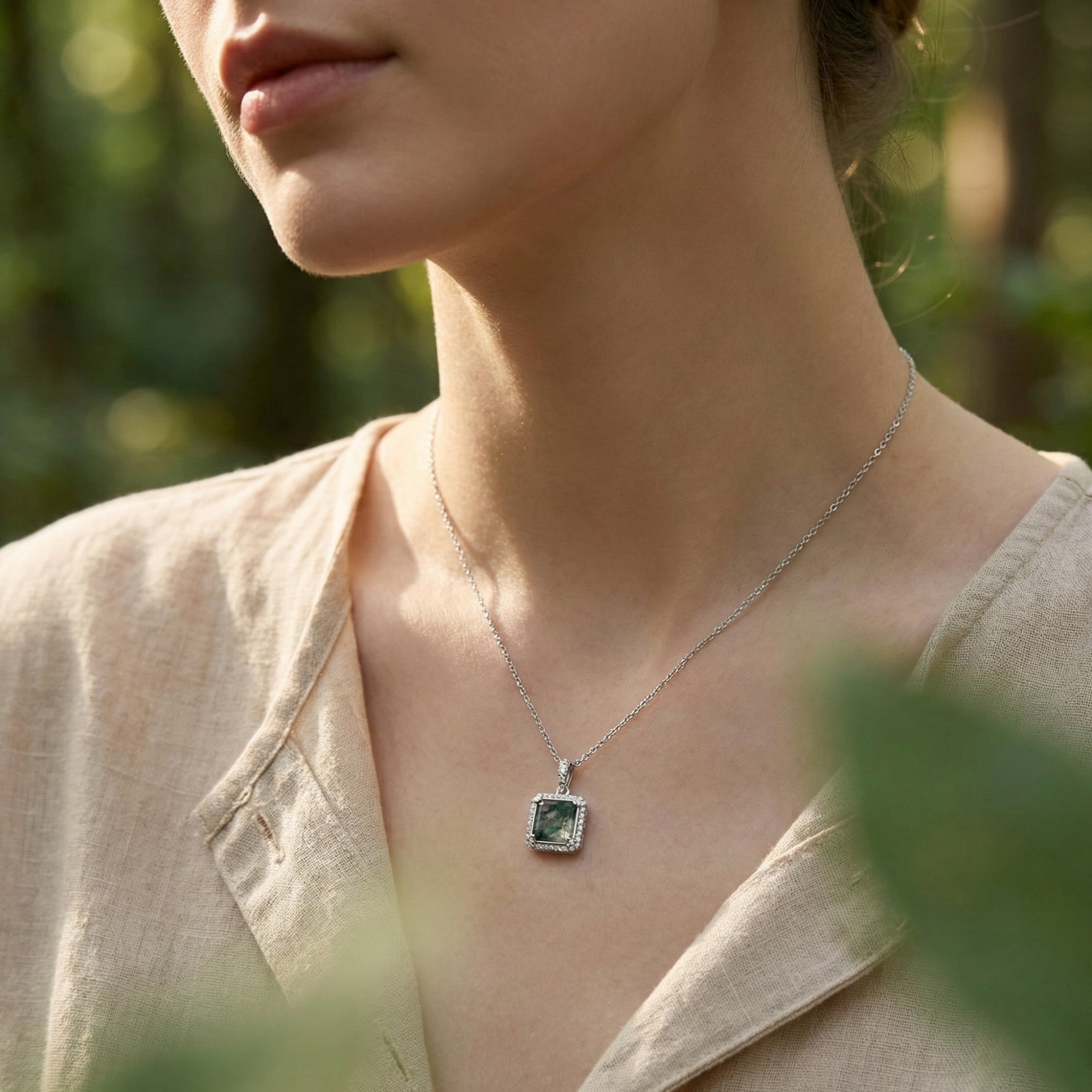Square cut moss agate halo necklace in sterling silver worn by a model in a natural outdoor setting.