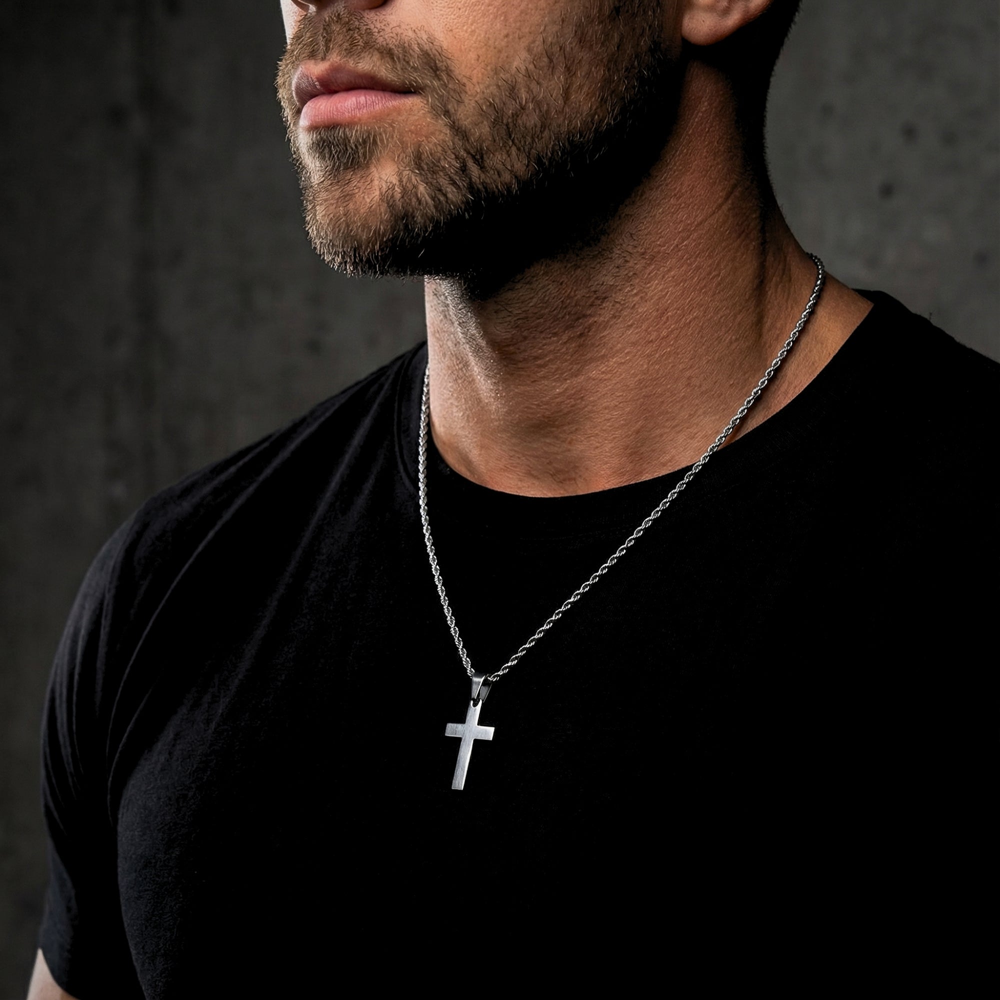 Male model wearing the silver stainless steel Apostle Cross pendant on a rope chain over a black t-shirt.