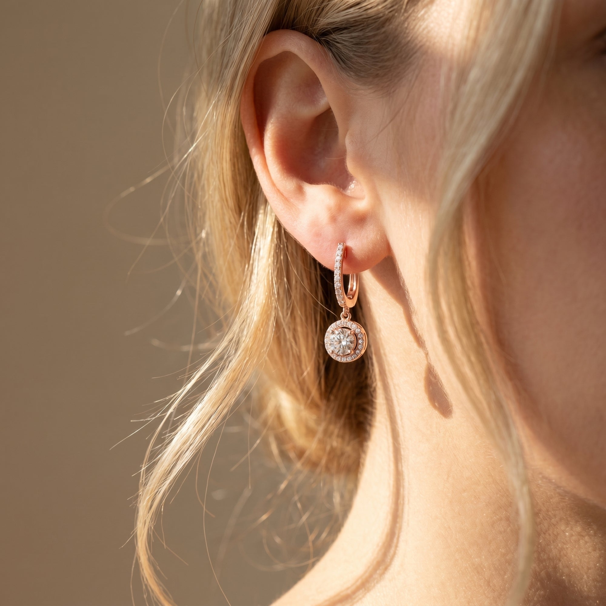 Rose gold round moissanite drop earring worn on a model's ear.