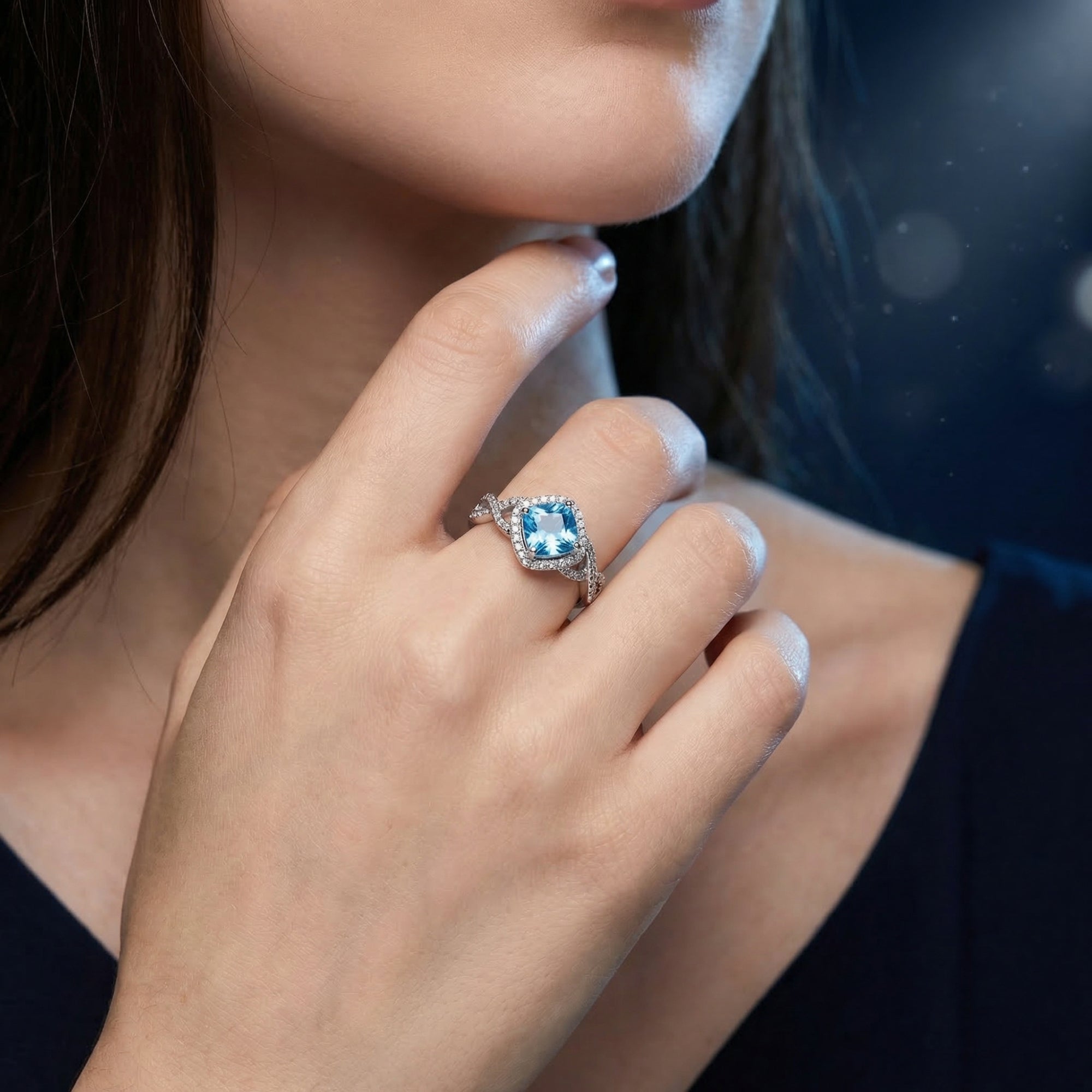 Sterling silver ring with a cushion cut Swiss blue topaz worn on a woman's hand.