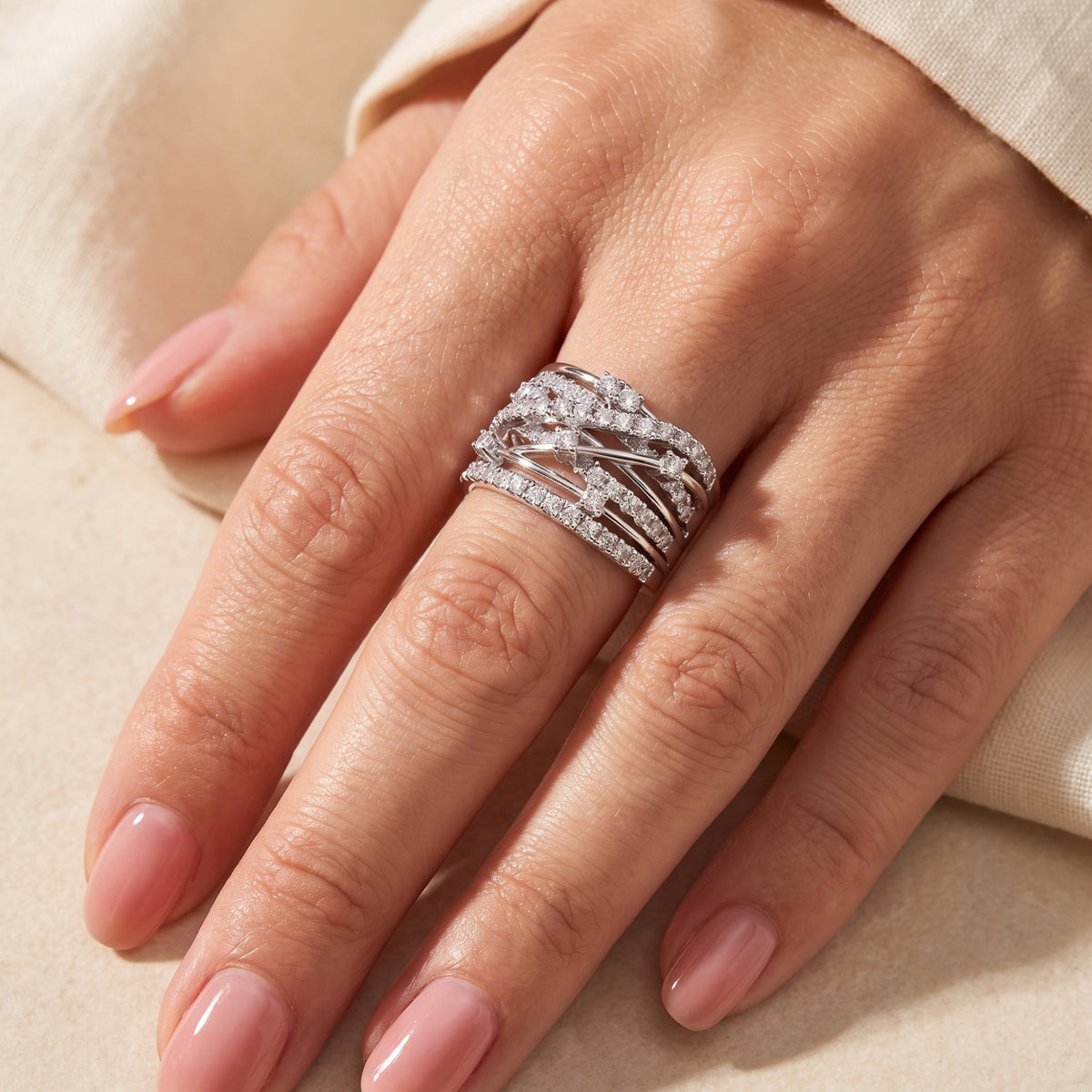 Close-up of a hand wearing the wide Aria criss-cross ring in solid white gold with A5 Cubic Zirconia accents.