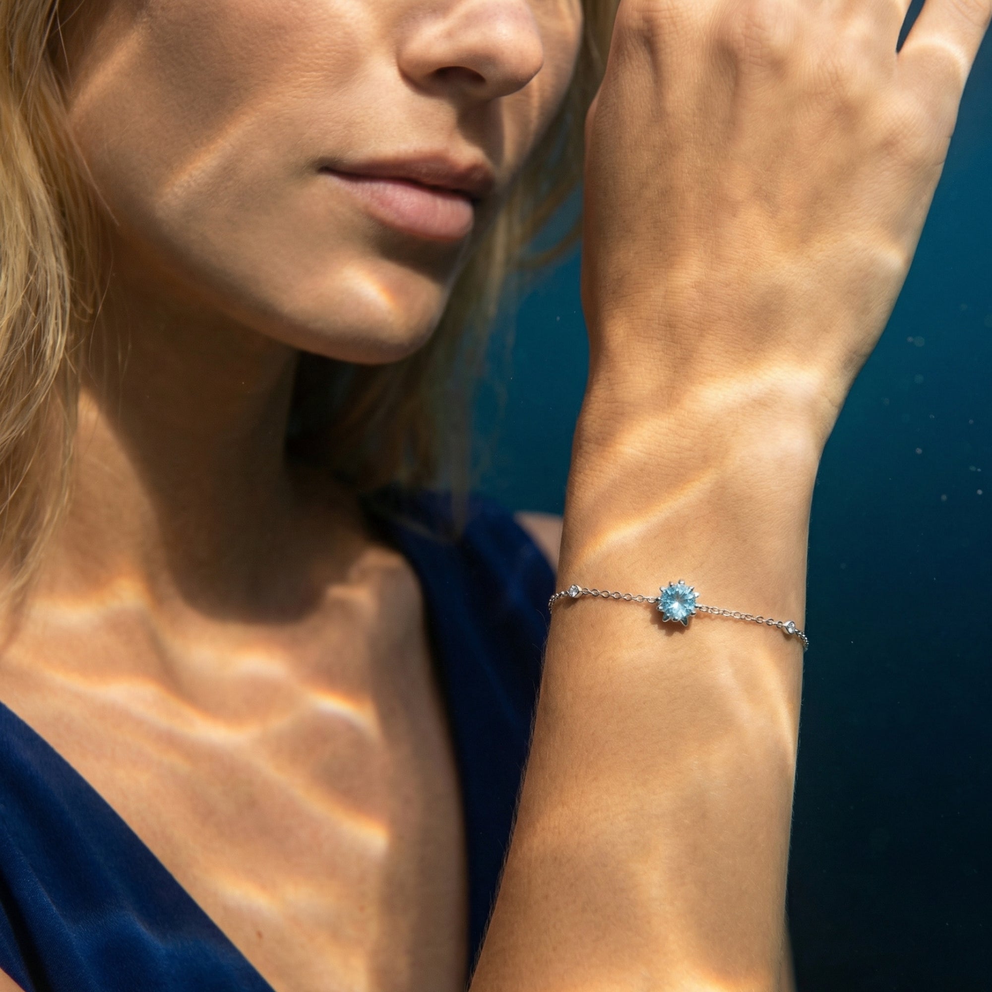 Natural aquamarine and platinum station bracelet shown on a model's wrist with soft lighting.