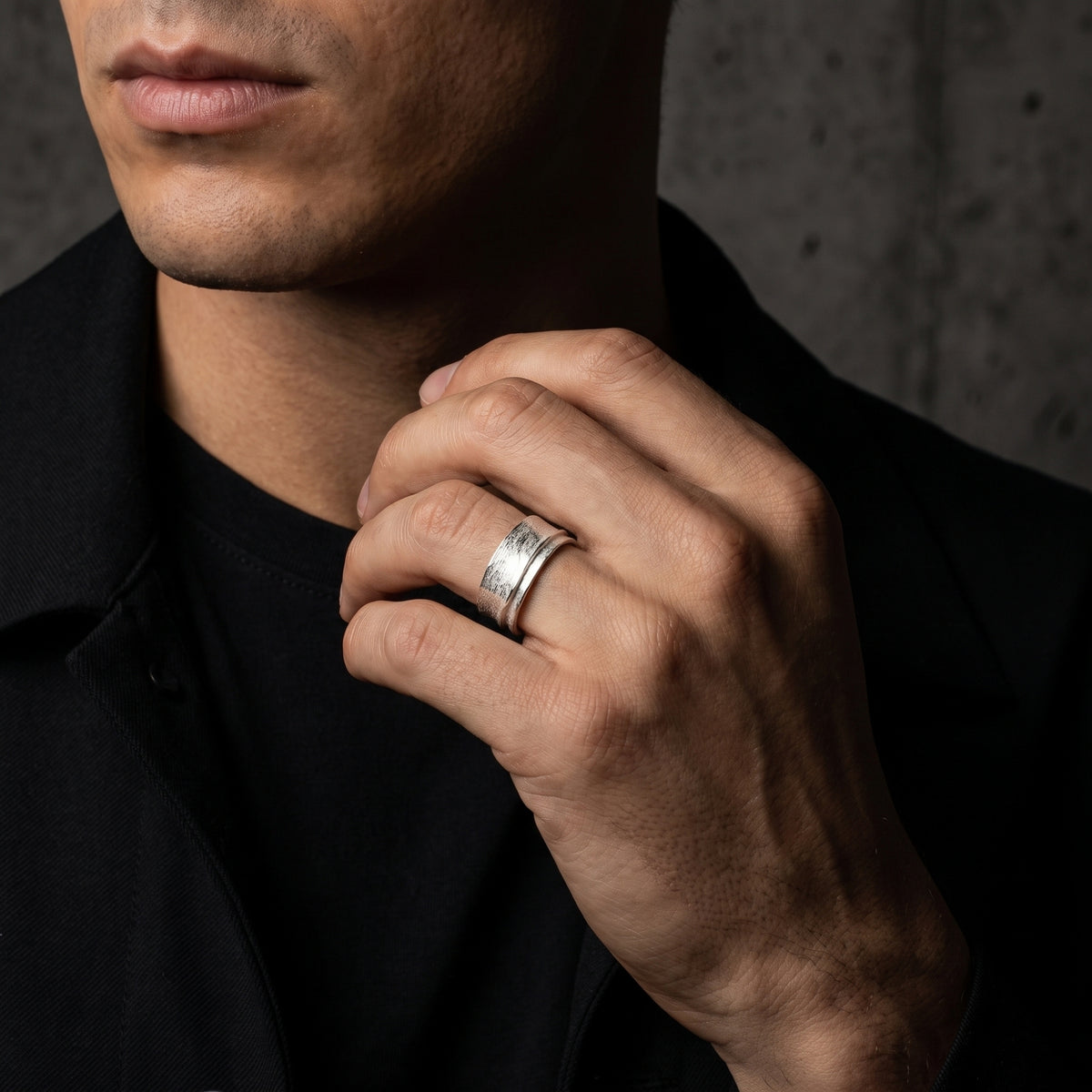 Close-up of a man wearing the textured silver overlap ring while holding his jacket collar