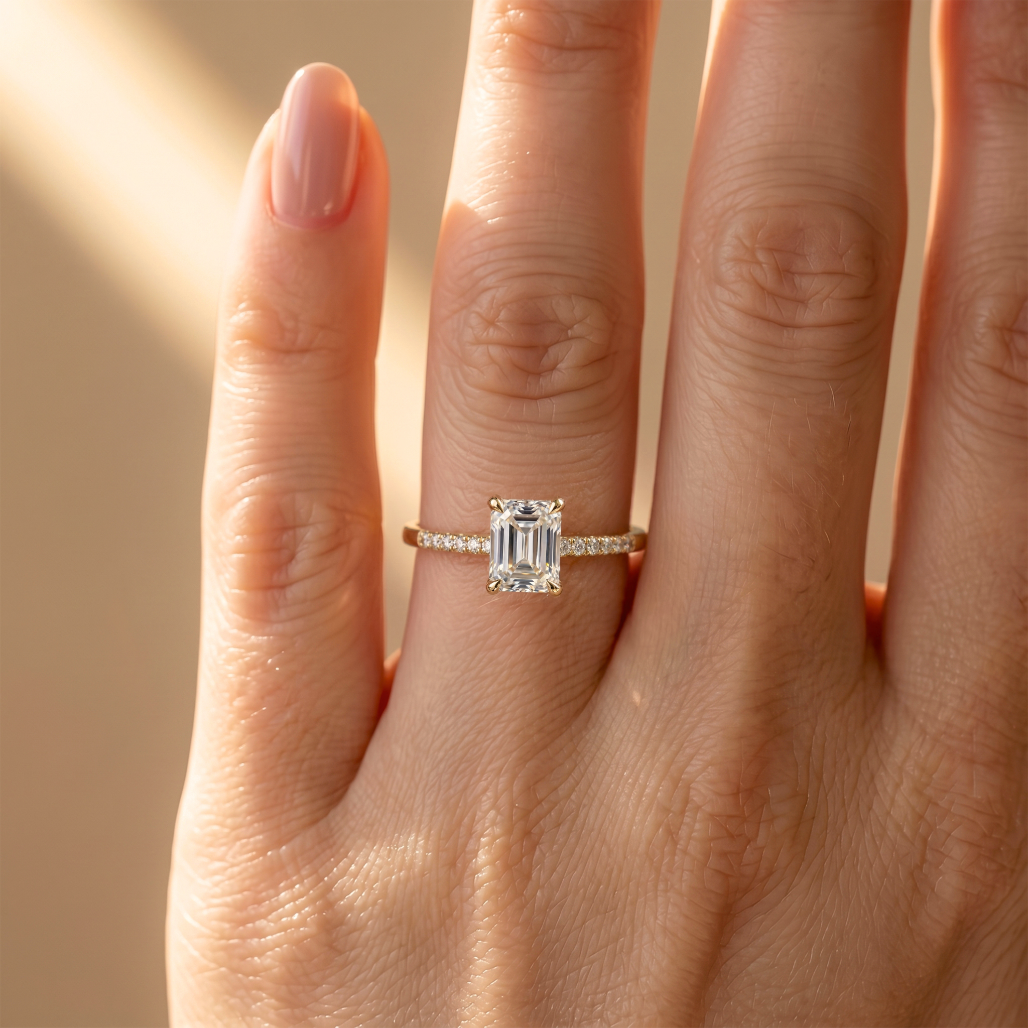 Close-up of a yellow gold emerald cut moissanite engagement ring showcased on a model's hand.