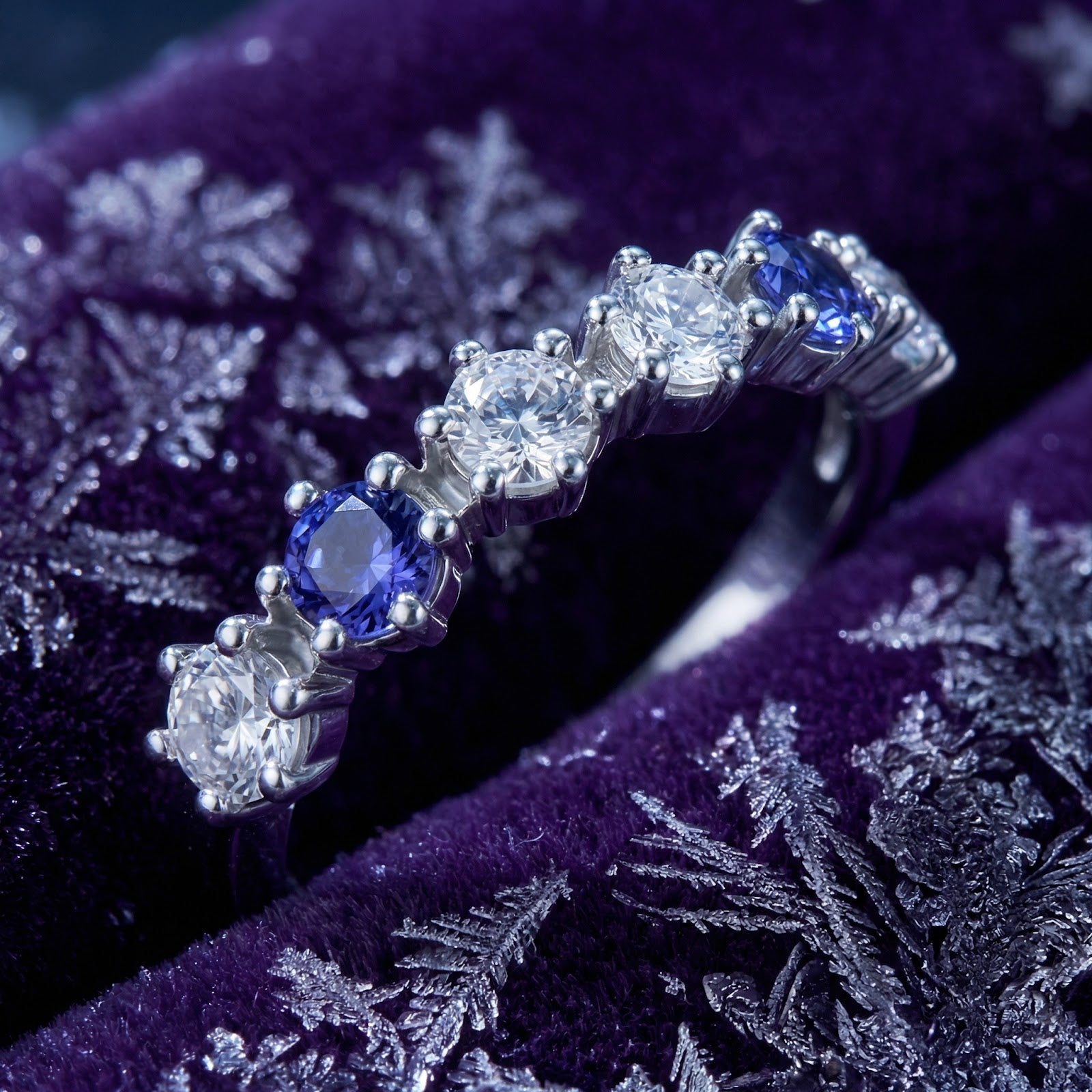 Detailed view of round-cut simulated tanzanite and clear stones on the S925 sterling silver Kyrianne Row ring.