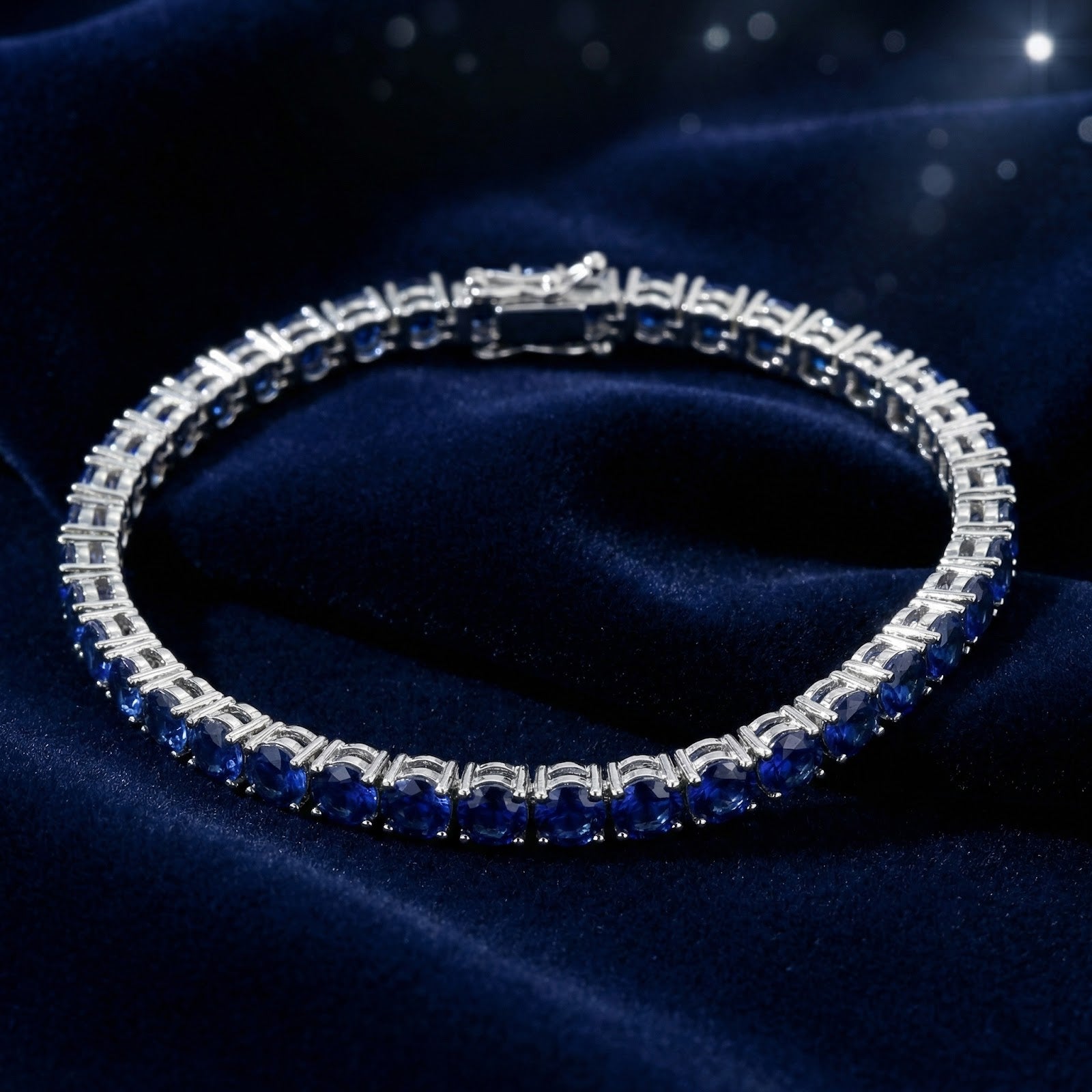 Silver stainless steel tennis bracelet with round royal blue simulated sapphires on dark blue velvet.