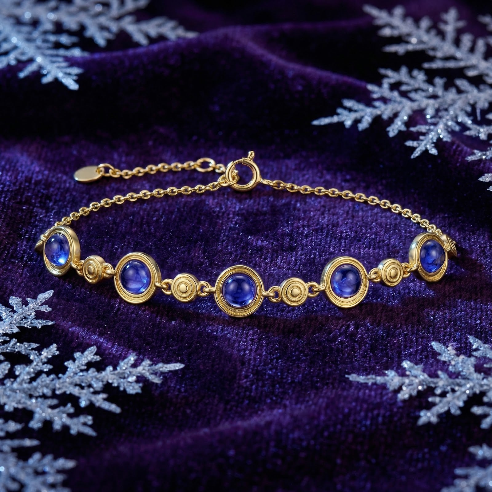 18K gold vermeil station bracelet with round simulated tanzanite on purple velvet with snowflake accents.