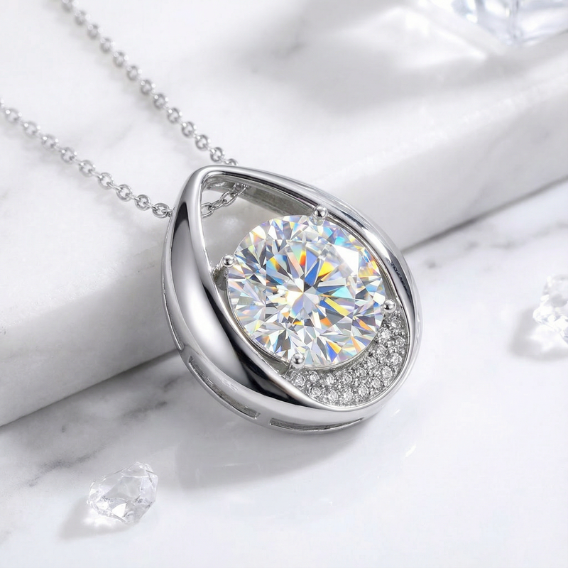 Side view of the sterling silver teardrop necklace featuring a round cut zirconia on a marble surface.