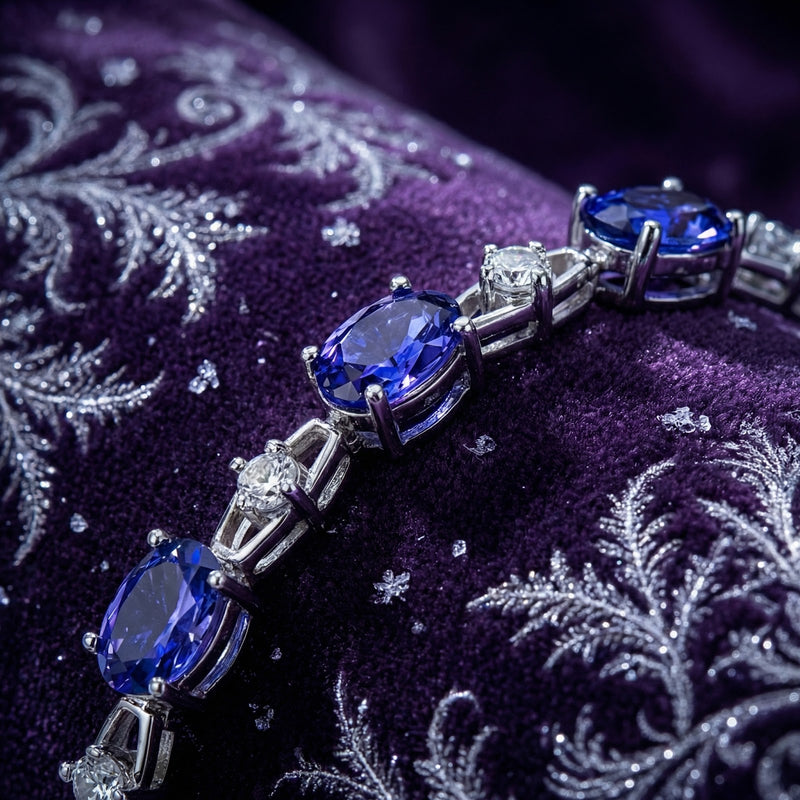 Close-up of oval simulated tanzanite and round clear stones in a sterling silver station bracelet setting.