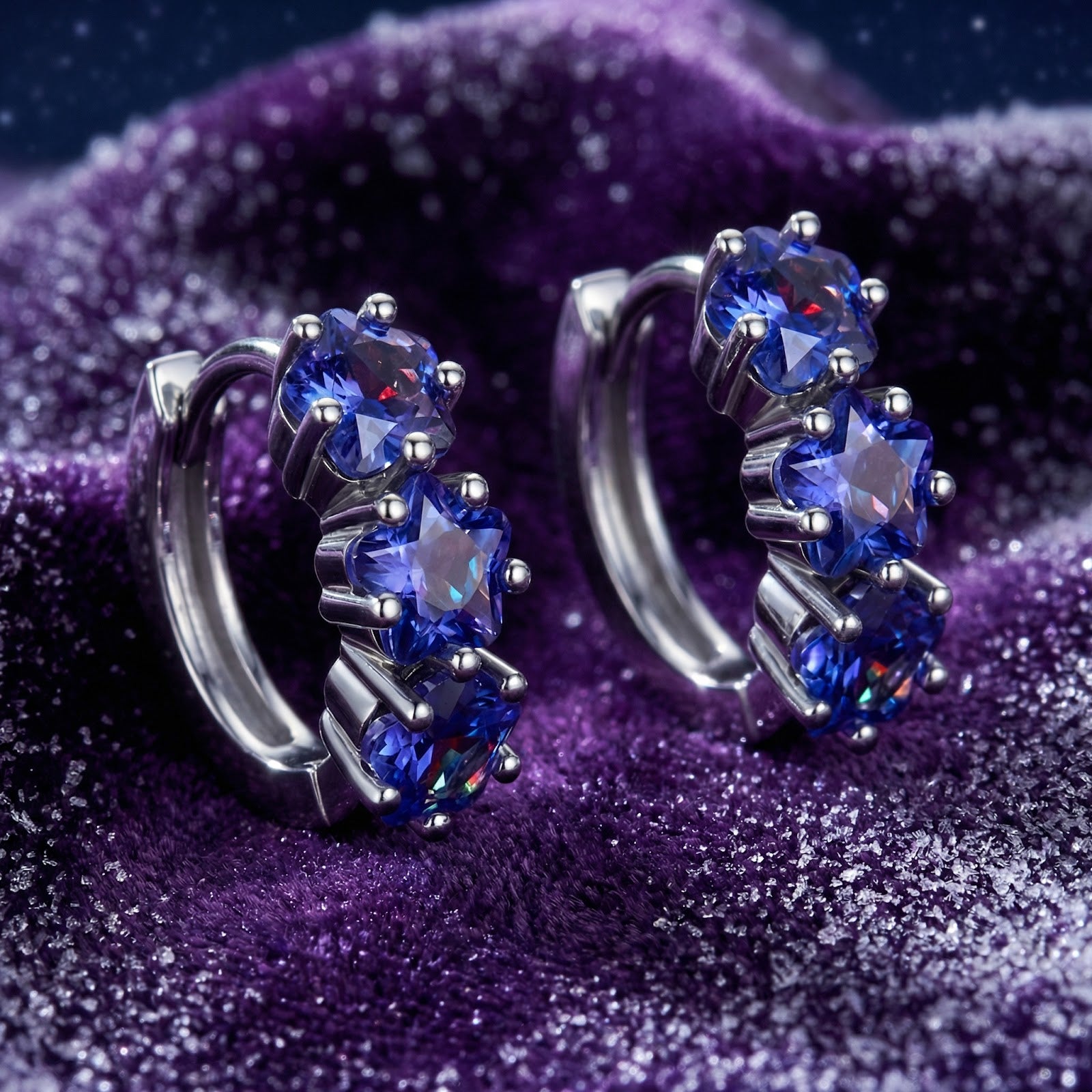 Sterling silver star huggie earrings with blue simulated tanzanite stones on a purple textured background.