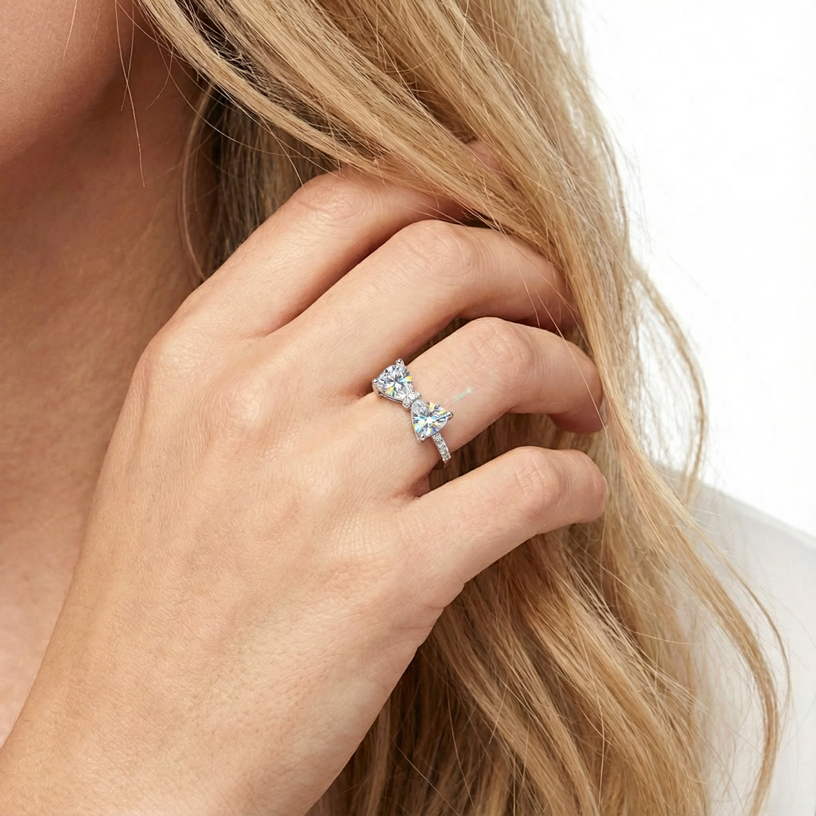 Sterling silver bow ring with trillion-cut simulated diamonds shown on a model's hand for scale.