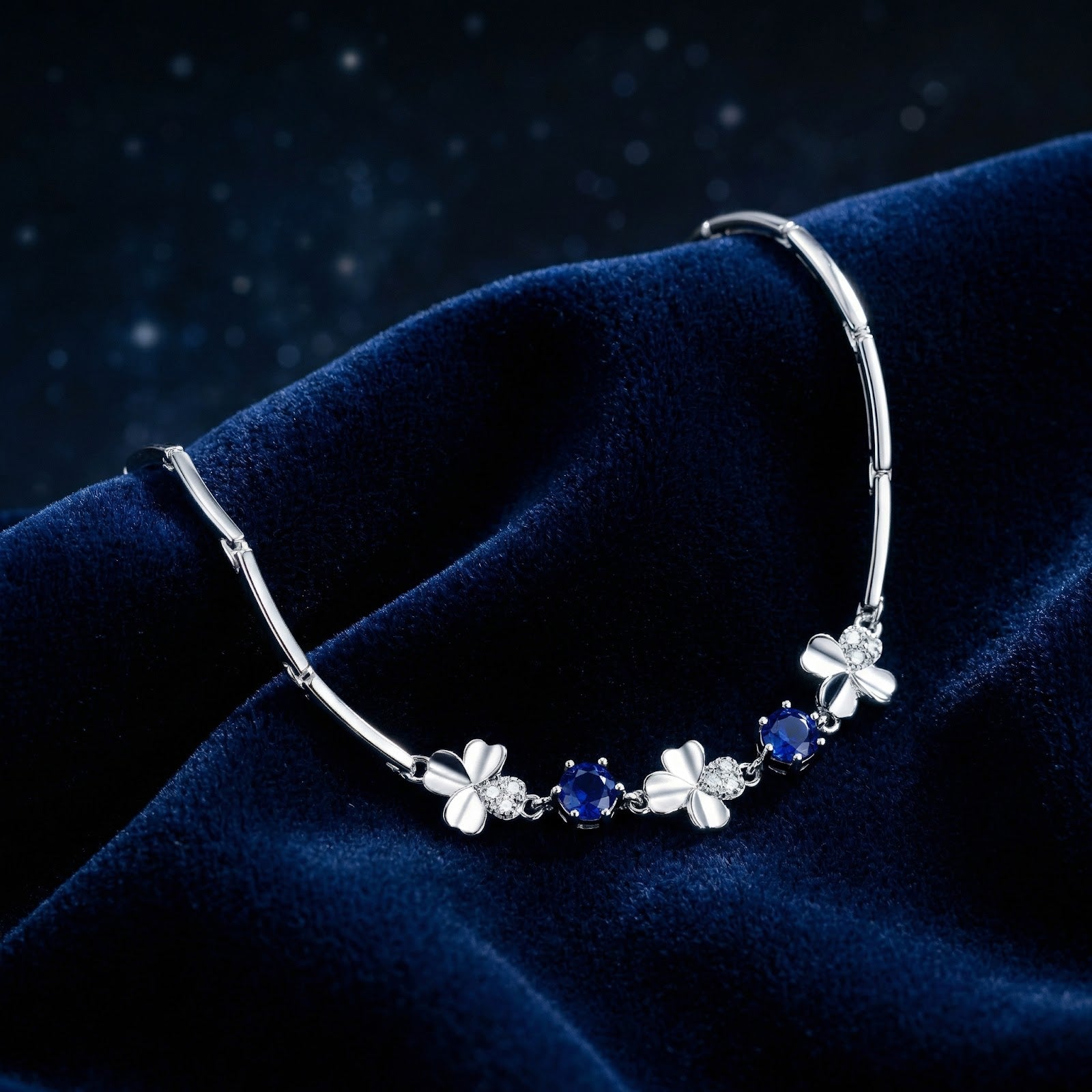 Close-up of the sterling silver clover motifs and round royal blue simulated sapphires on a velvet surface.