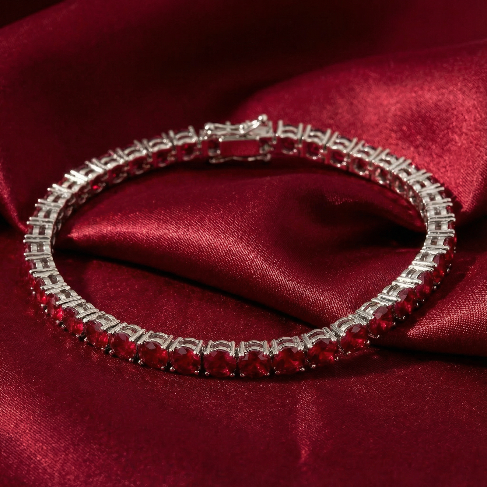 Adalira July birthstone tennis bracelet with round simulated rubies on a red satin fabric background.