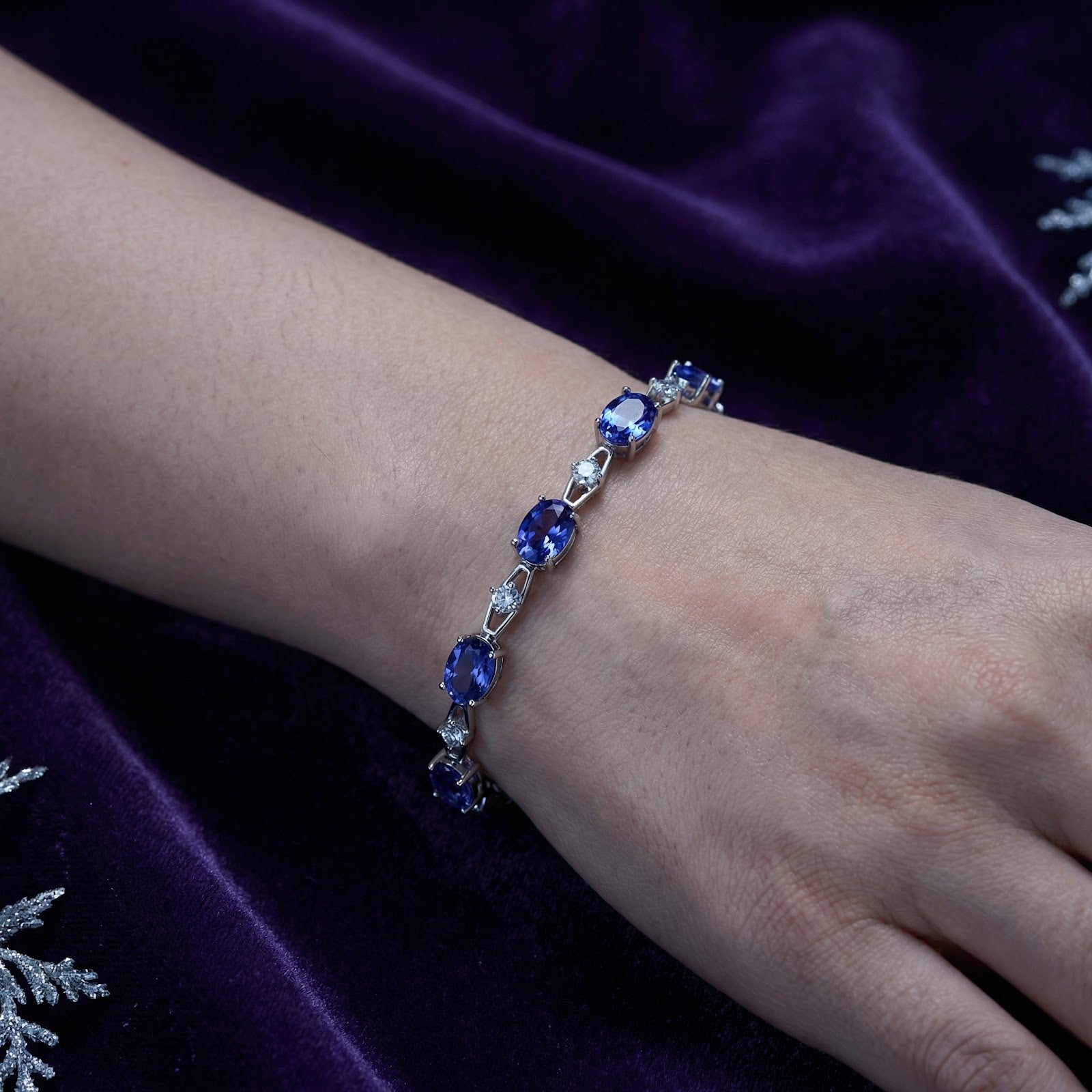 Sterling silver station bracelet with oval simulated tanzanite stones worn on a woman's wrist.