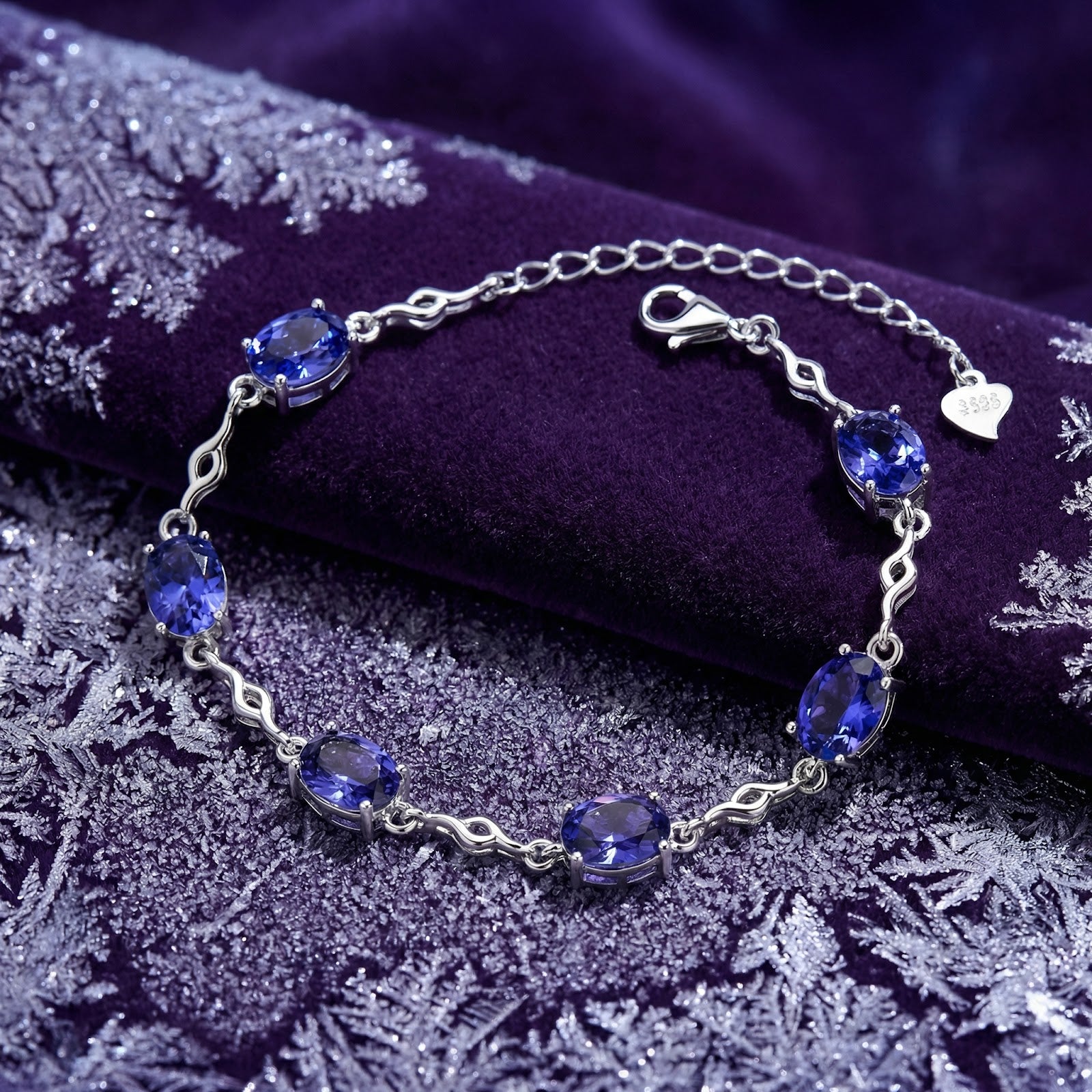 Melisara oval-cut simulated tanzanite station bracelet in sterling silver on purple velvet with snowflakes.