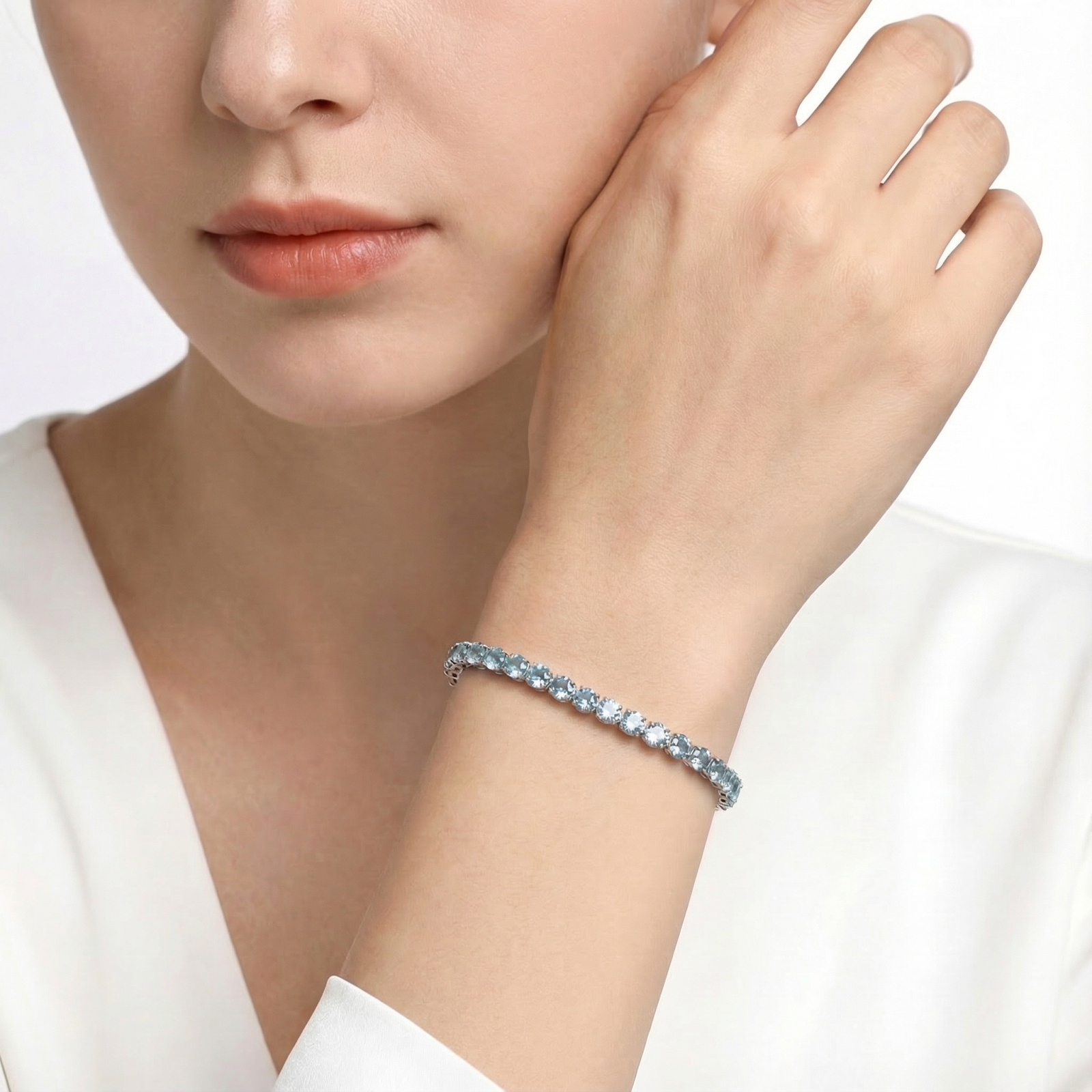 Close-up of the round cut simulated aquamarine stainless steel tennis bracelet on a model's wrist.
