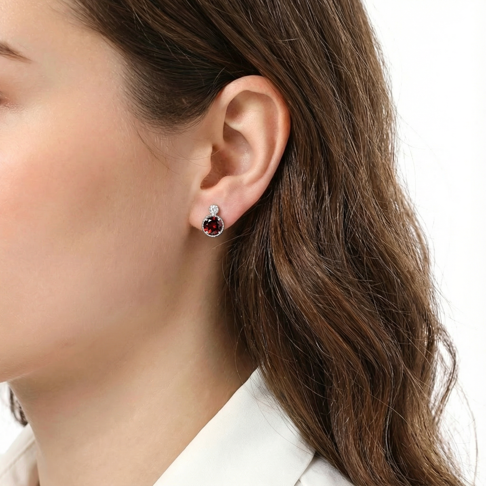 Woman wearing a round red garnet halo stud earring in sterling silver against a plain white background.