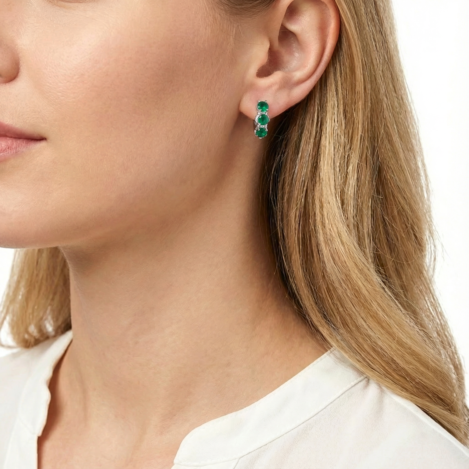 Side view of a model wearing the Sidraea star-cut green emerald sterling silver huggie earring.