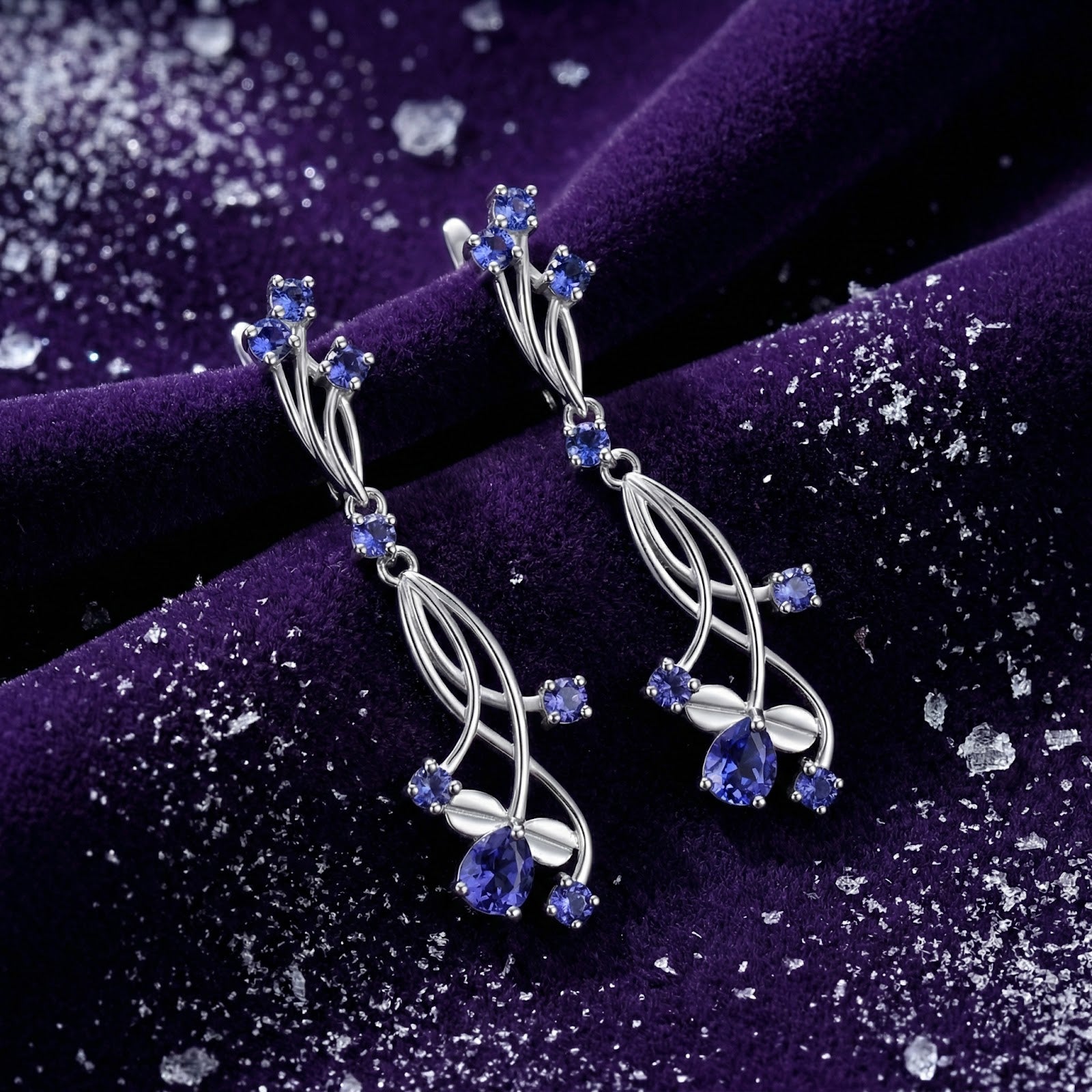 Thalinea drop earrings in S925 sterling silver with pear and round cut simulated tanzanite on purple velvet.