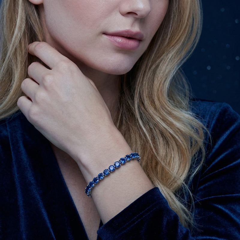 Royal blue simulated sapphire tennis bracelet in silver stainless steel worn on a woman's wrist.