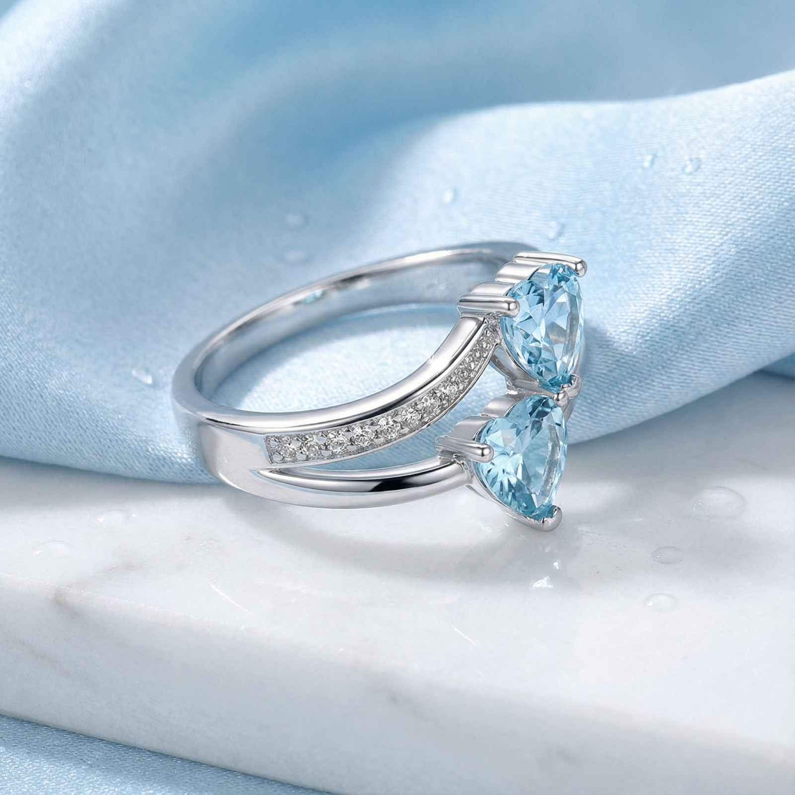 Macro side view of the heart-cut simulated aquamarine stones and pavé setting on a sterling silver bypass ring.