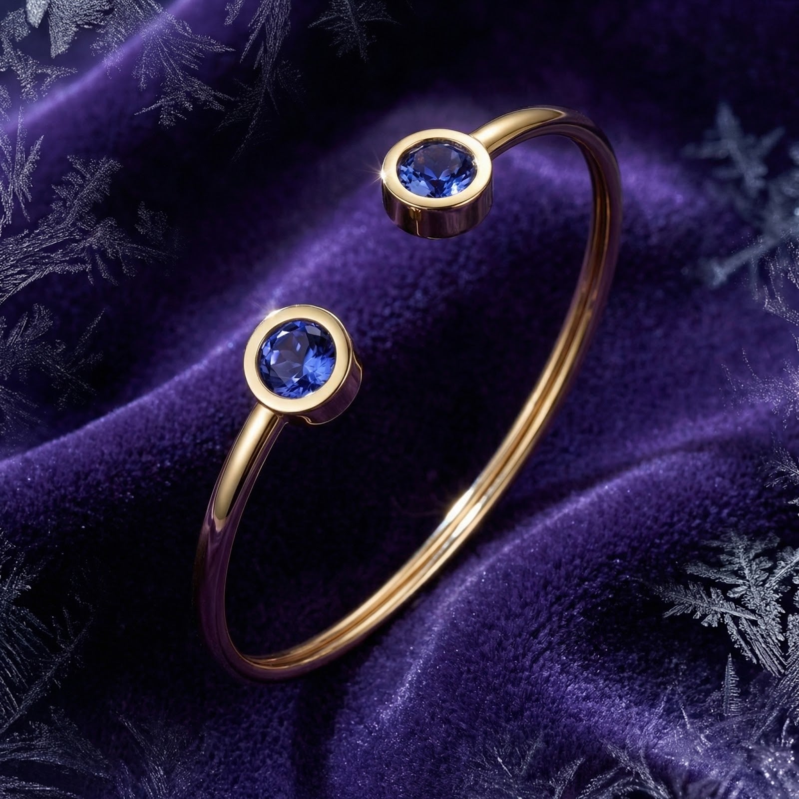 Gold stainless steel Veralis cuff featuring round blue simulated tanzanite stones on purple velvet.